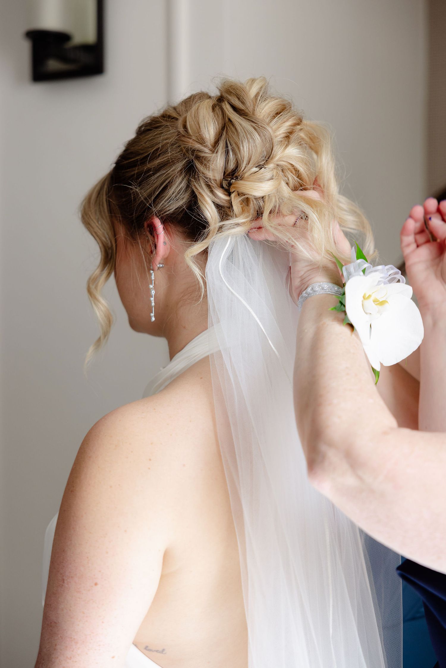 Elegant bridal hairstyle with intricate braids and curls adorned with a flowing white veil and floral accessory.