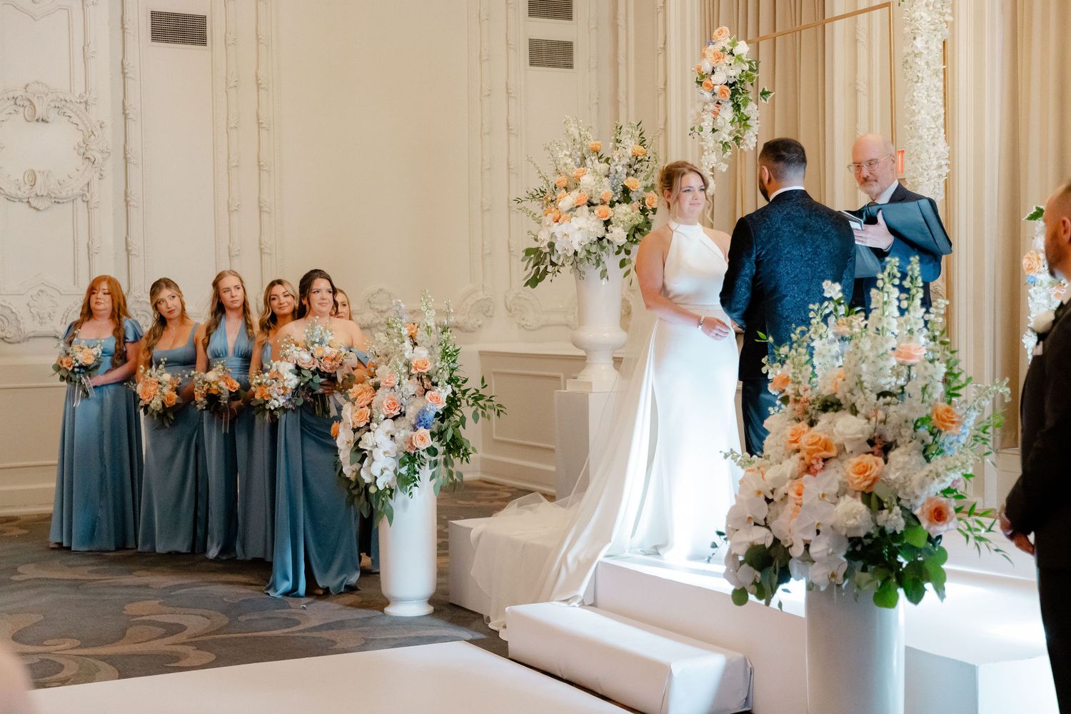 Wedding venue decorated with peach and white floral arrangements along the aisle.