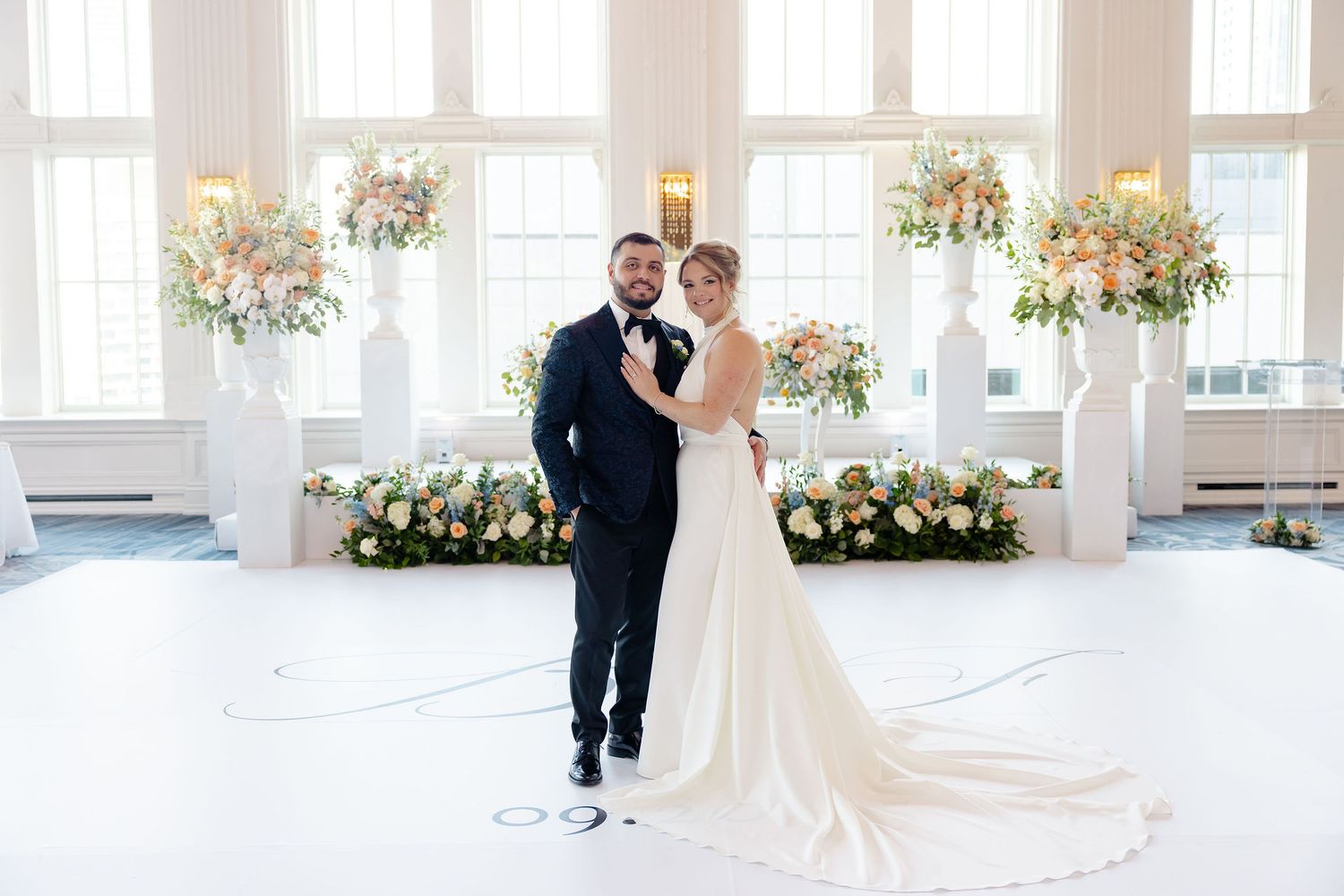 Bright, airy wedding venue decorated with romantic floral arrangements and large windows.
