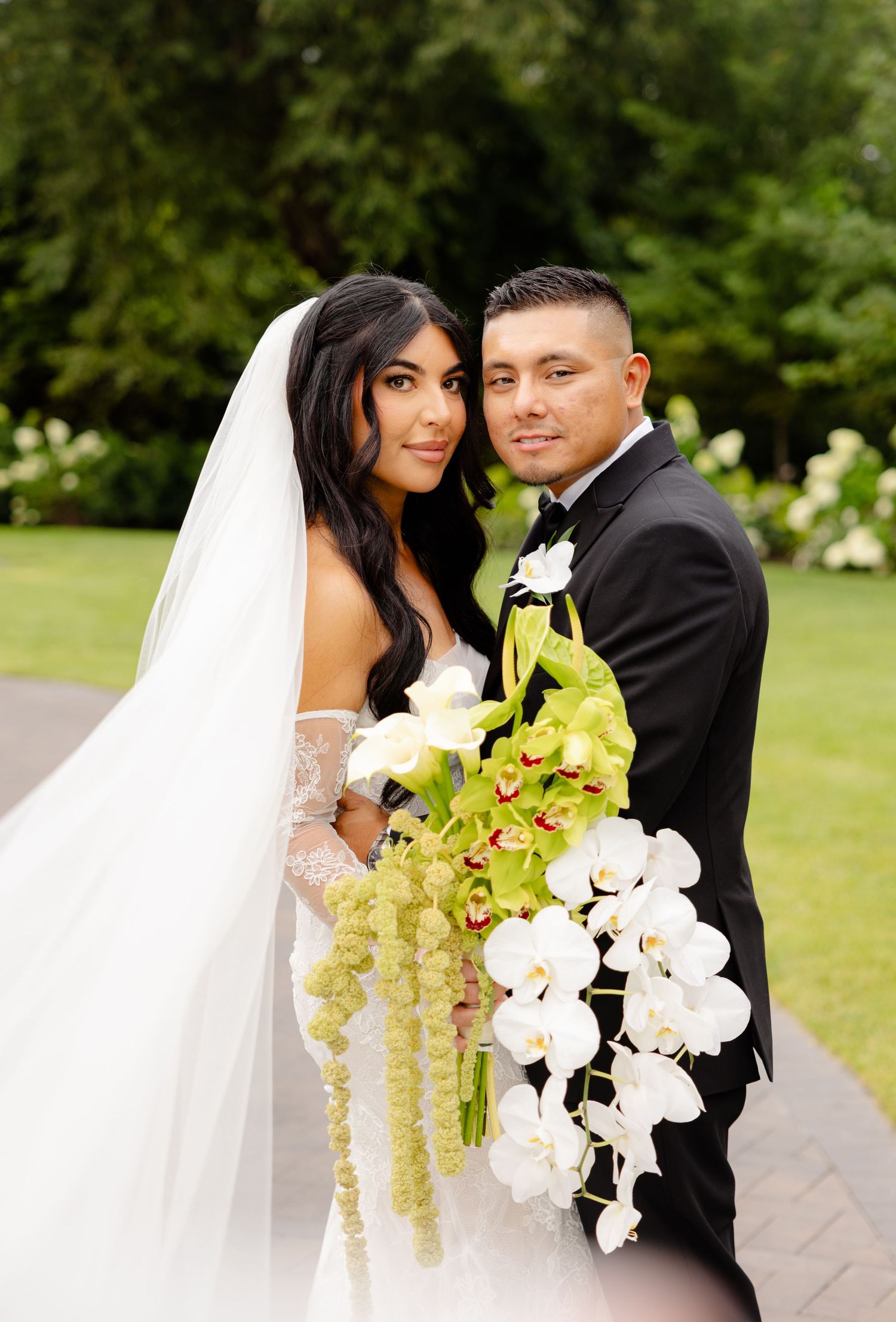 Bride and groom share romantic moment outdoors with stunning white and chartreuse orchid bouquet.
