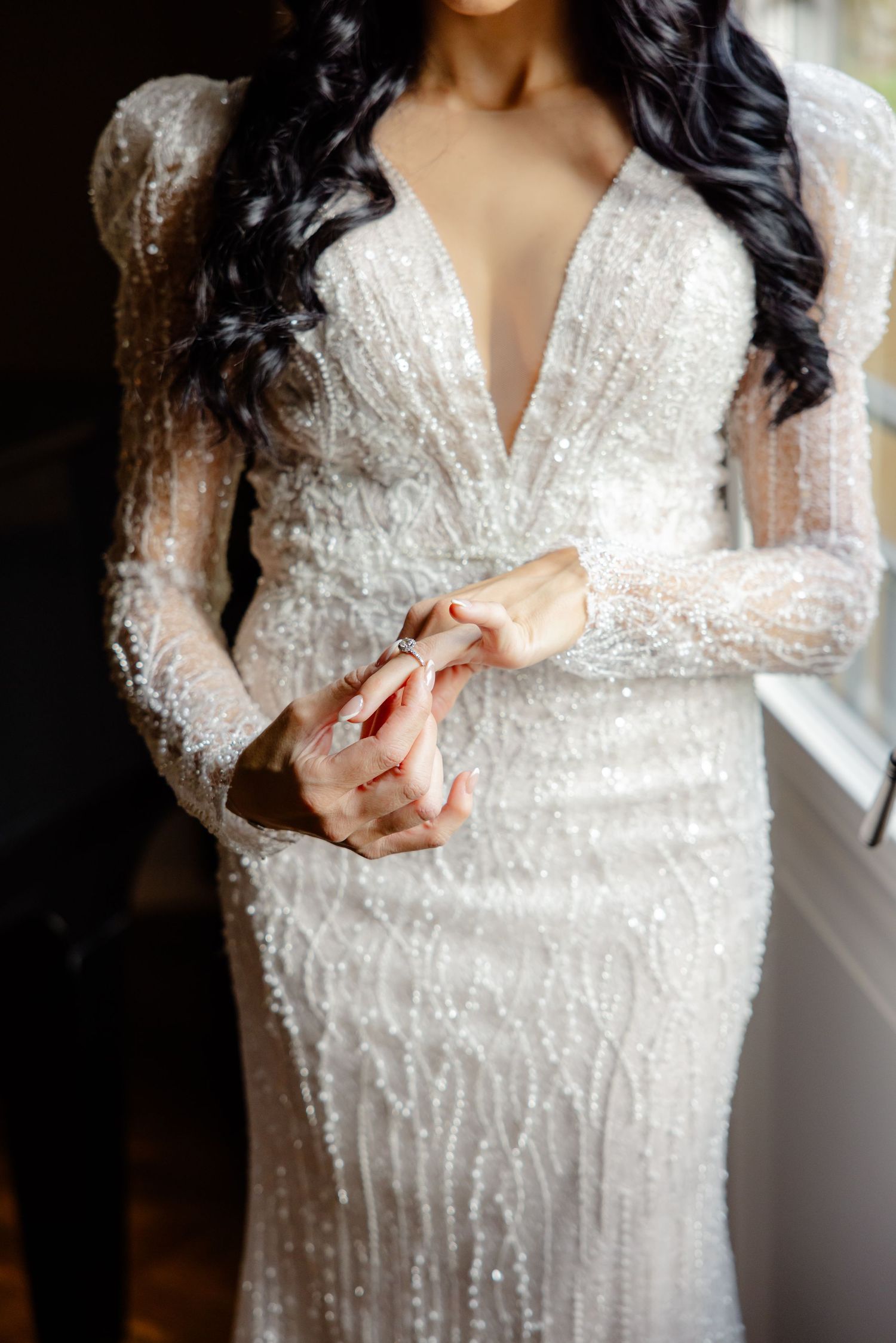 Close-up of an elegant beaded wedding dress with long sleeves and deep v-neckline.