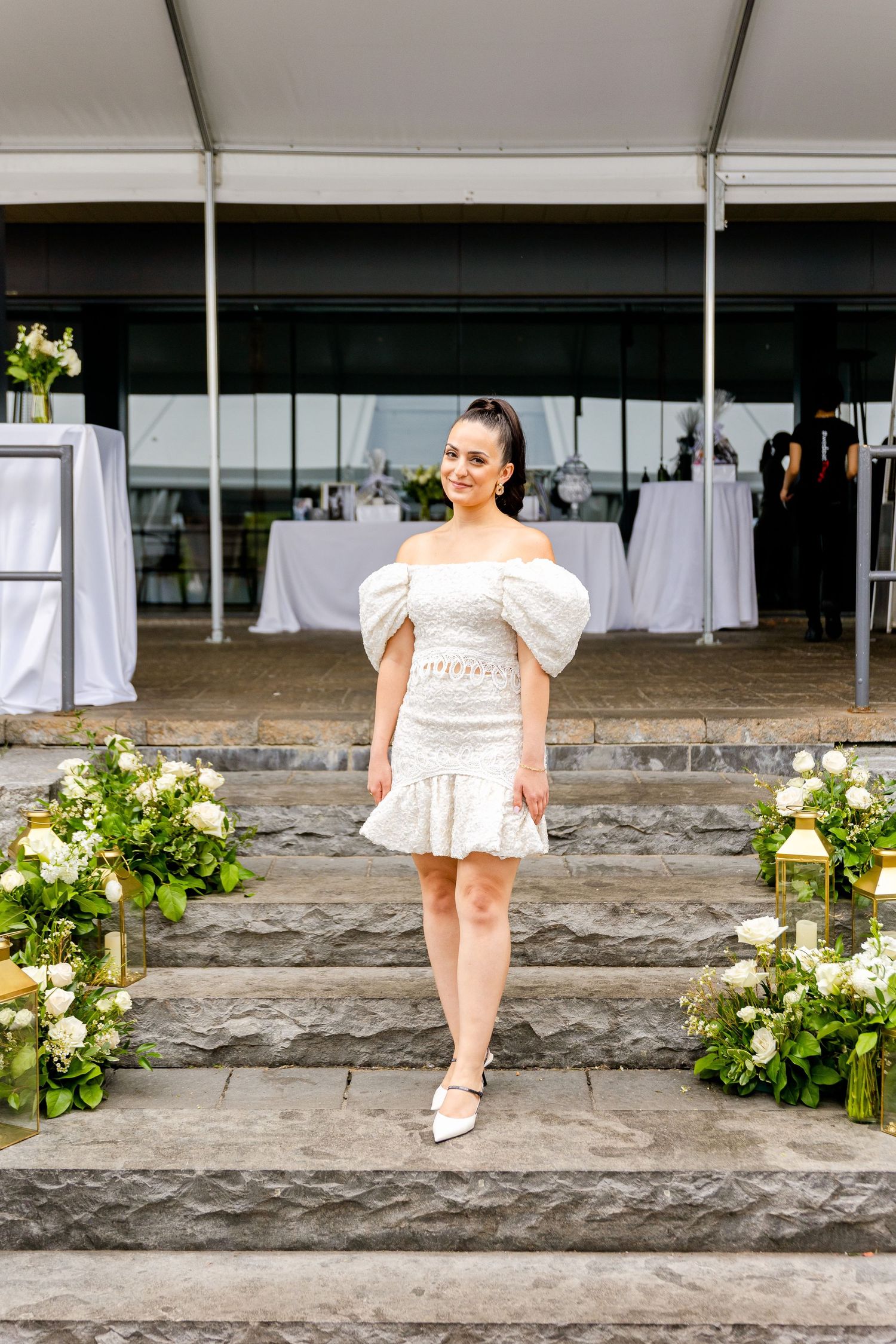 Stone steps adorned with floral arrangements lead to an elegant tented event space.