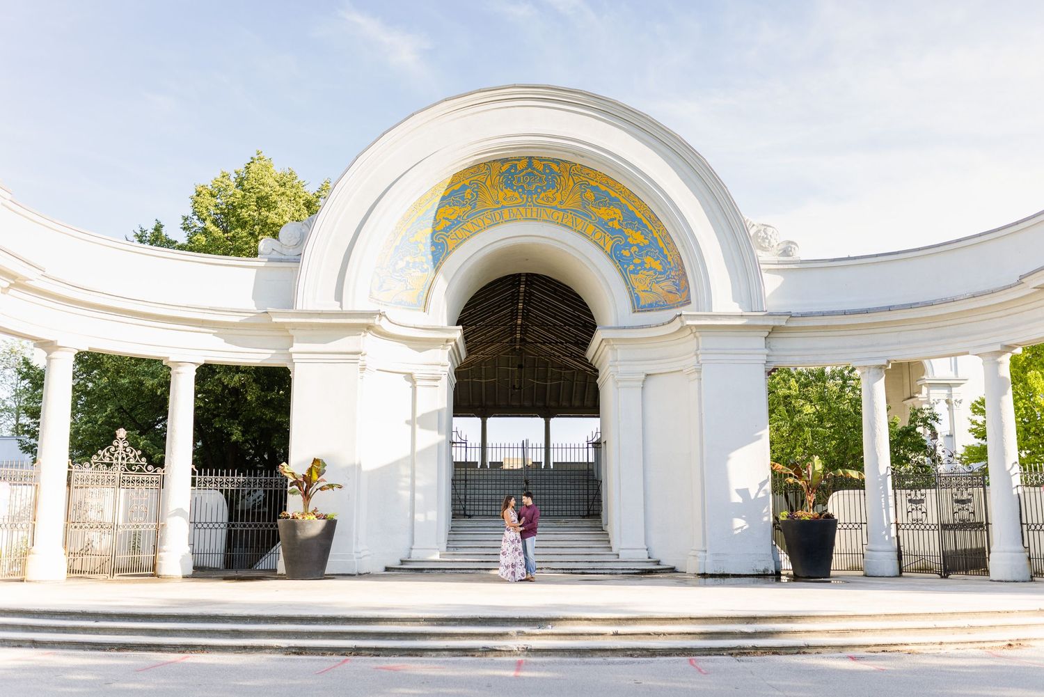 A grand white archway entrance with decorative mosaic ceiling and classical columns.