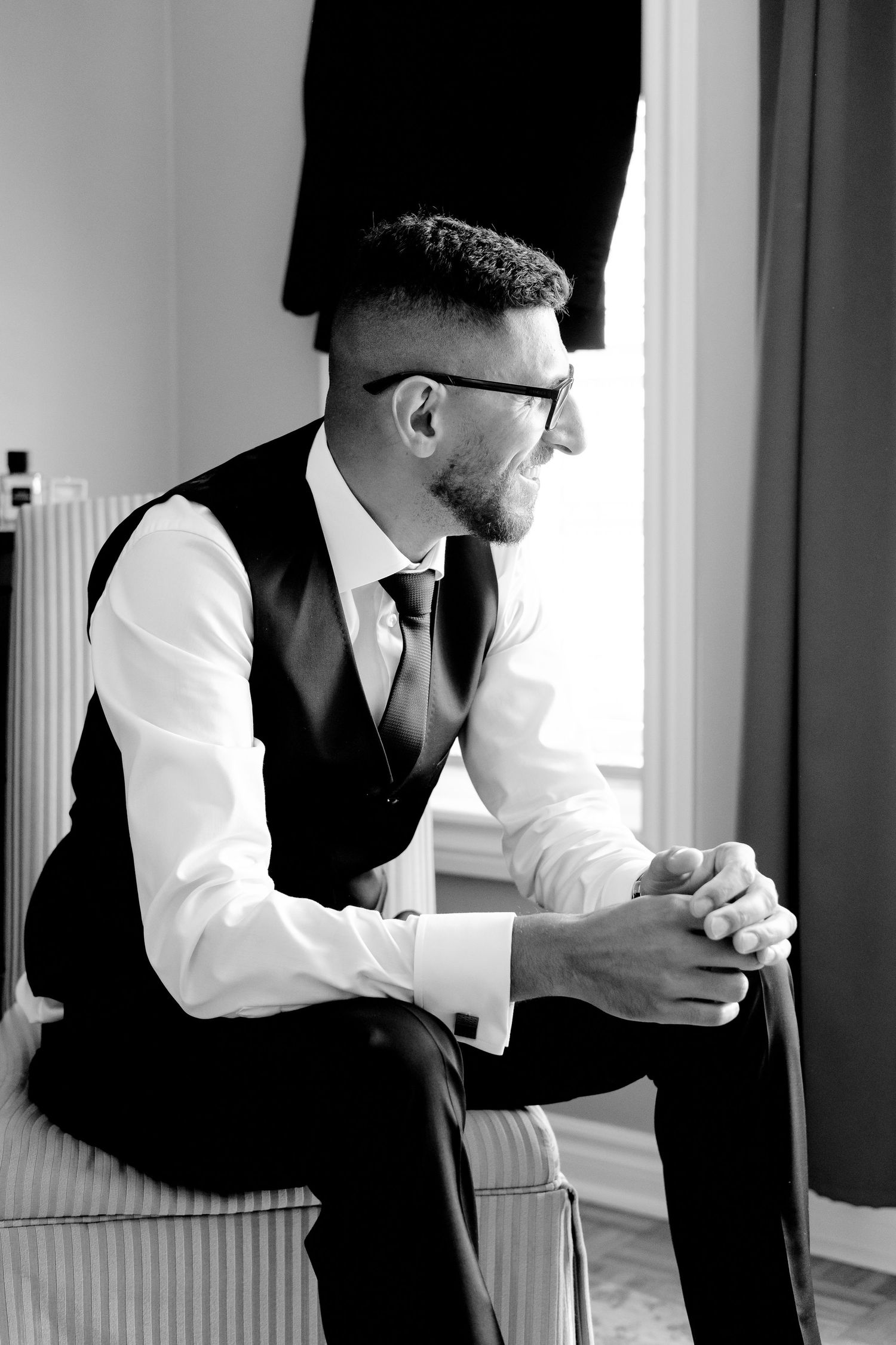 Side profile of someone in formal attire sitting thoughtfully on a chair.