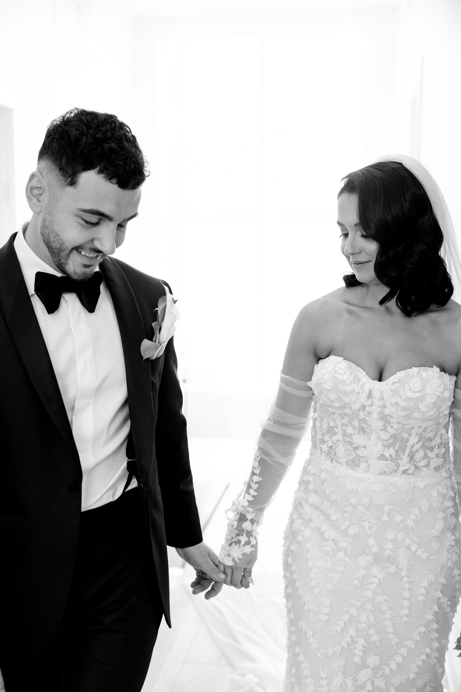 Black and white portrait of newlyweds holding hands and sharing tender moment.