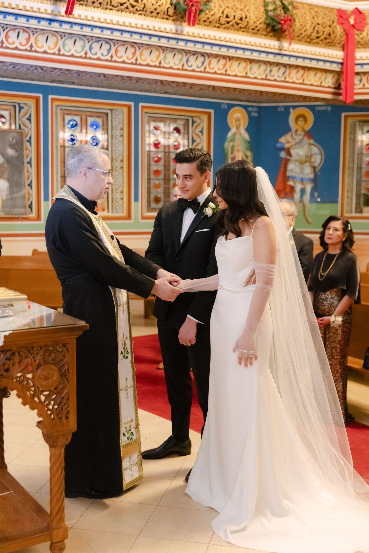 Traditional orthodox wedding ceremony with priest officiating in ornately decorated church.