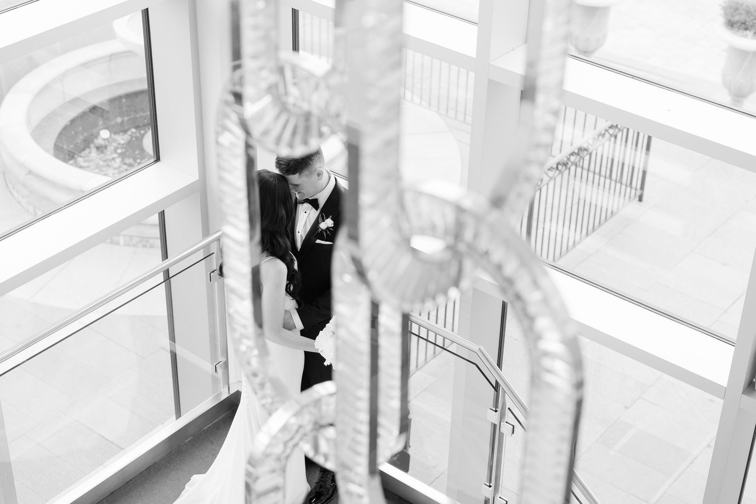 Black and white photograph through chandelier crystals on modern staircase landing.