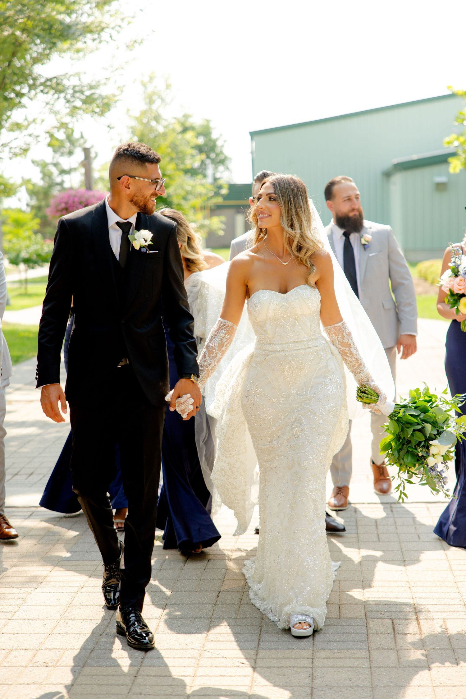 Wedding couple walking together outdoors, bride in white lace gown.