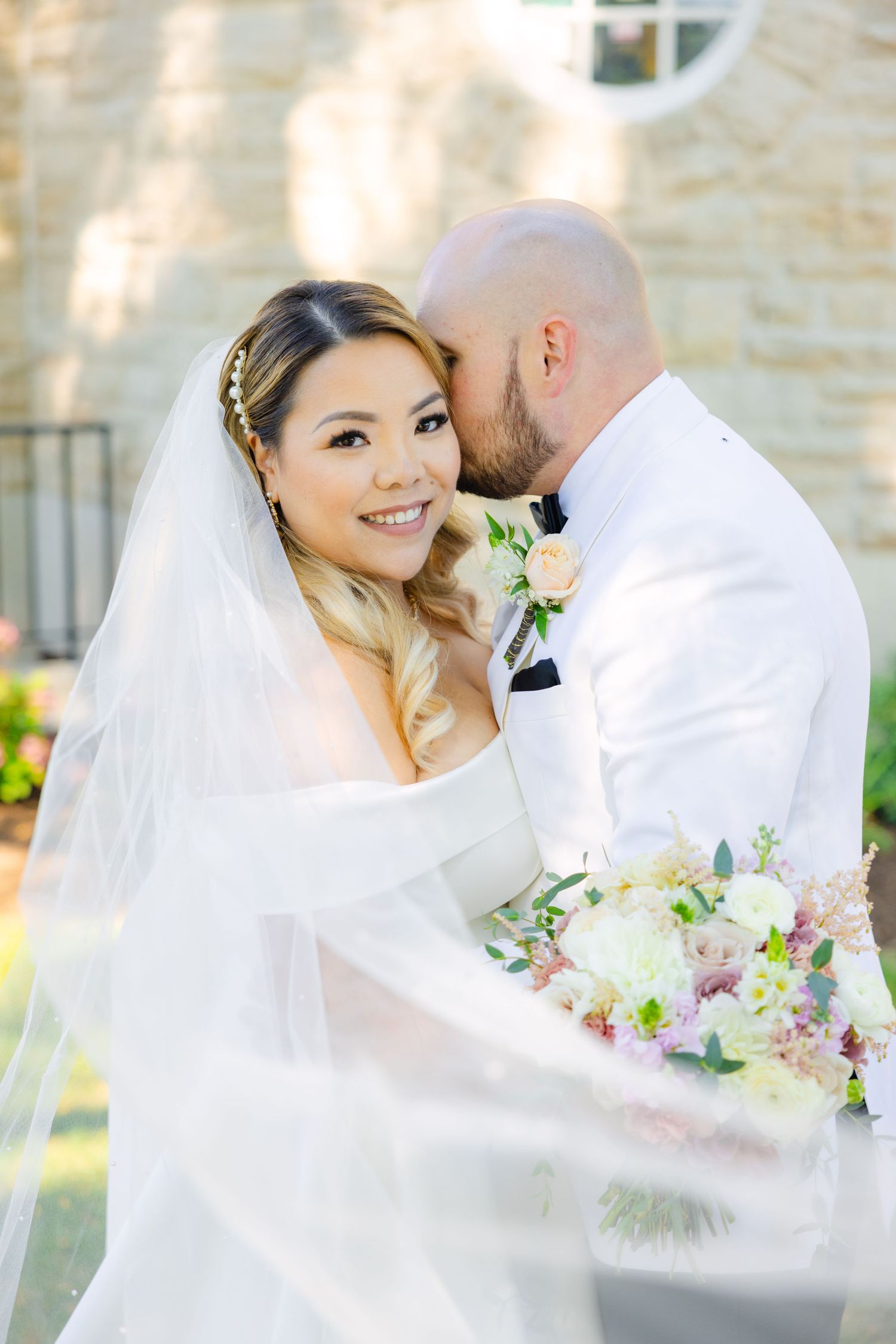 A joyful wedding portrait with delicate florals and flowing veil in natural light.