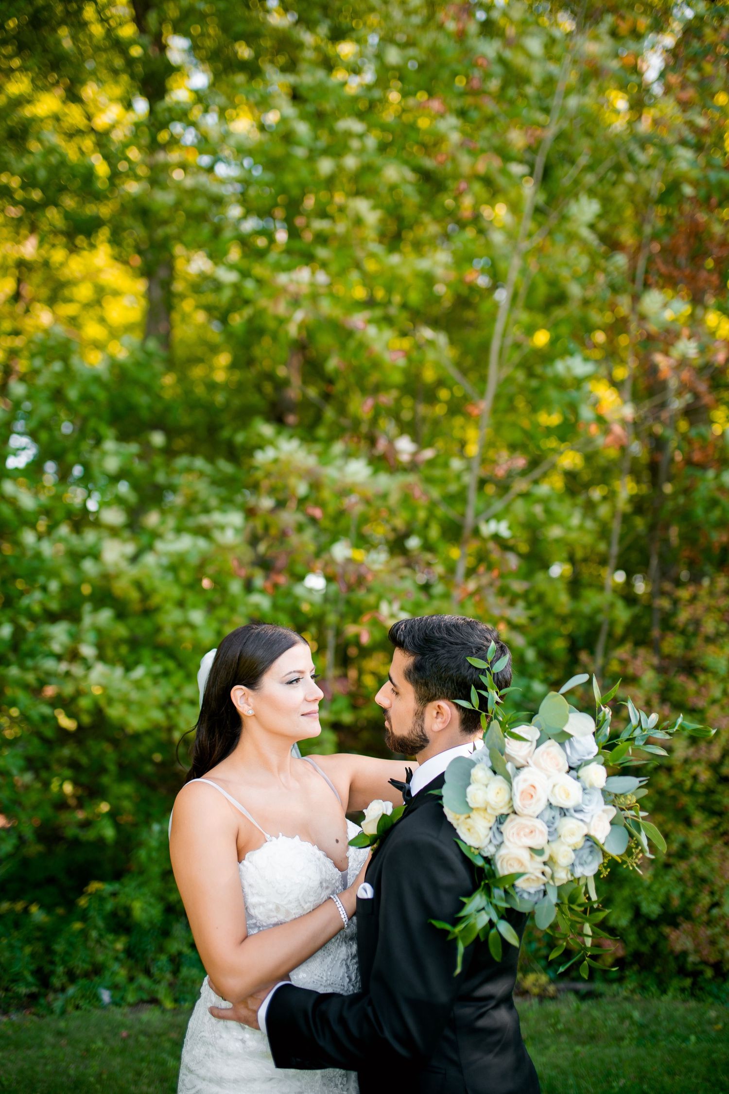 Romantic outdoor wedding portrait with lush greenery background.