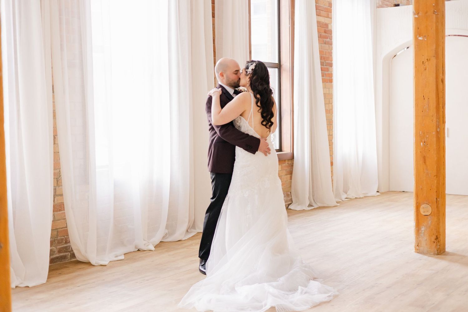 An intimate dance moment in a bright studio space with wooden columns.