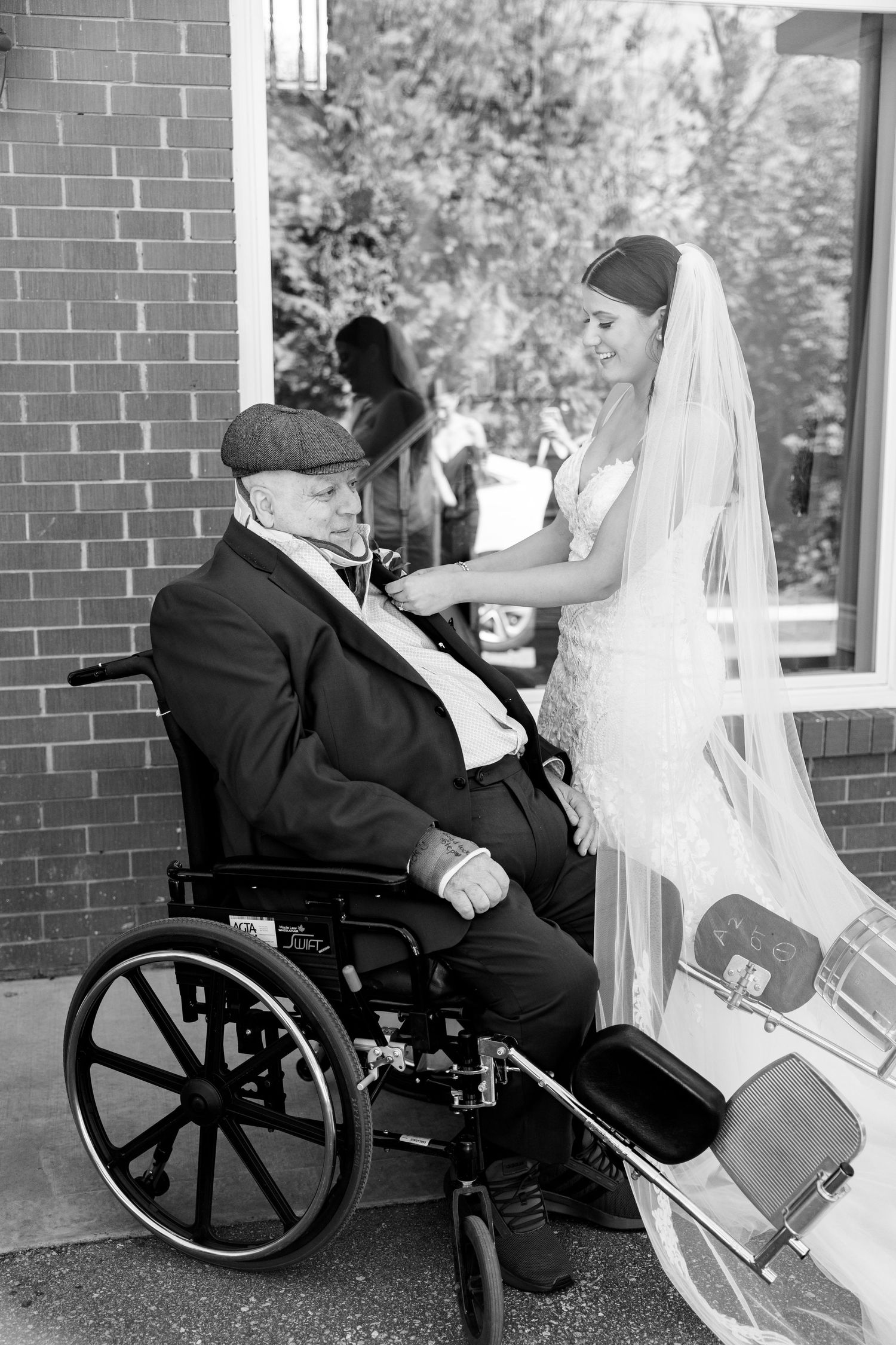 Black and white portrait of tender wedding moment on brick porch.
