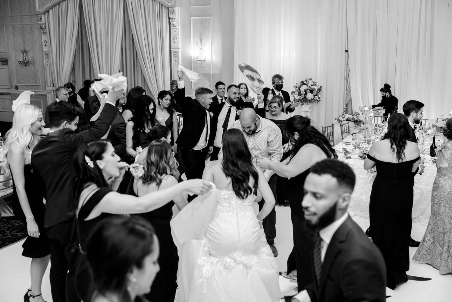 Black and white photo of wedding guests dancing and celebrating on a packed dance floor.