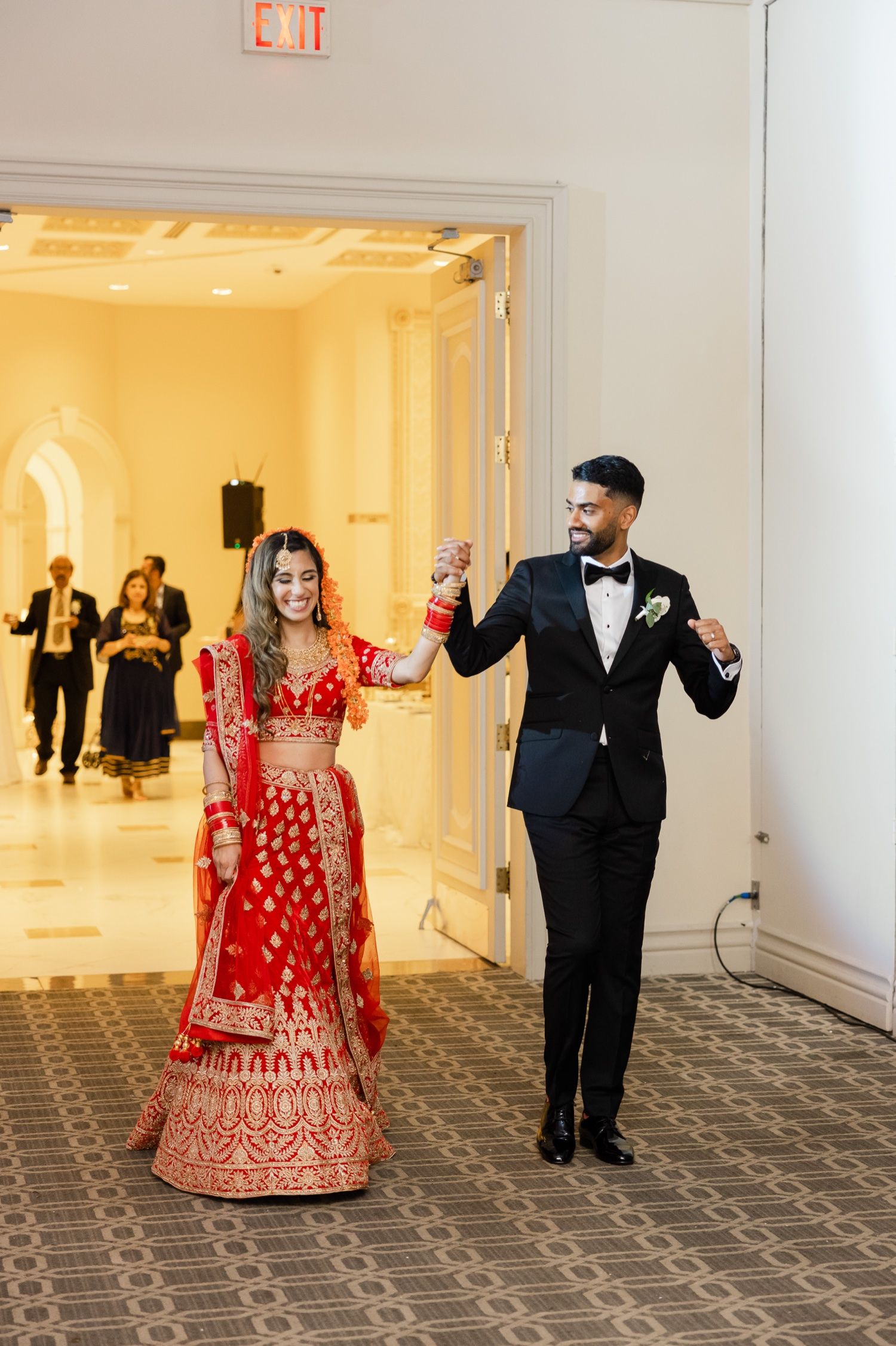 A couple makes their grand entrance at their wedding reception in formal cultural attire.