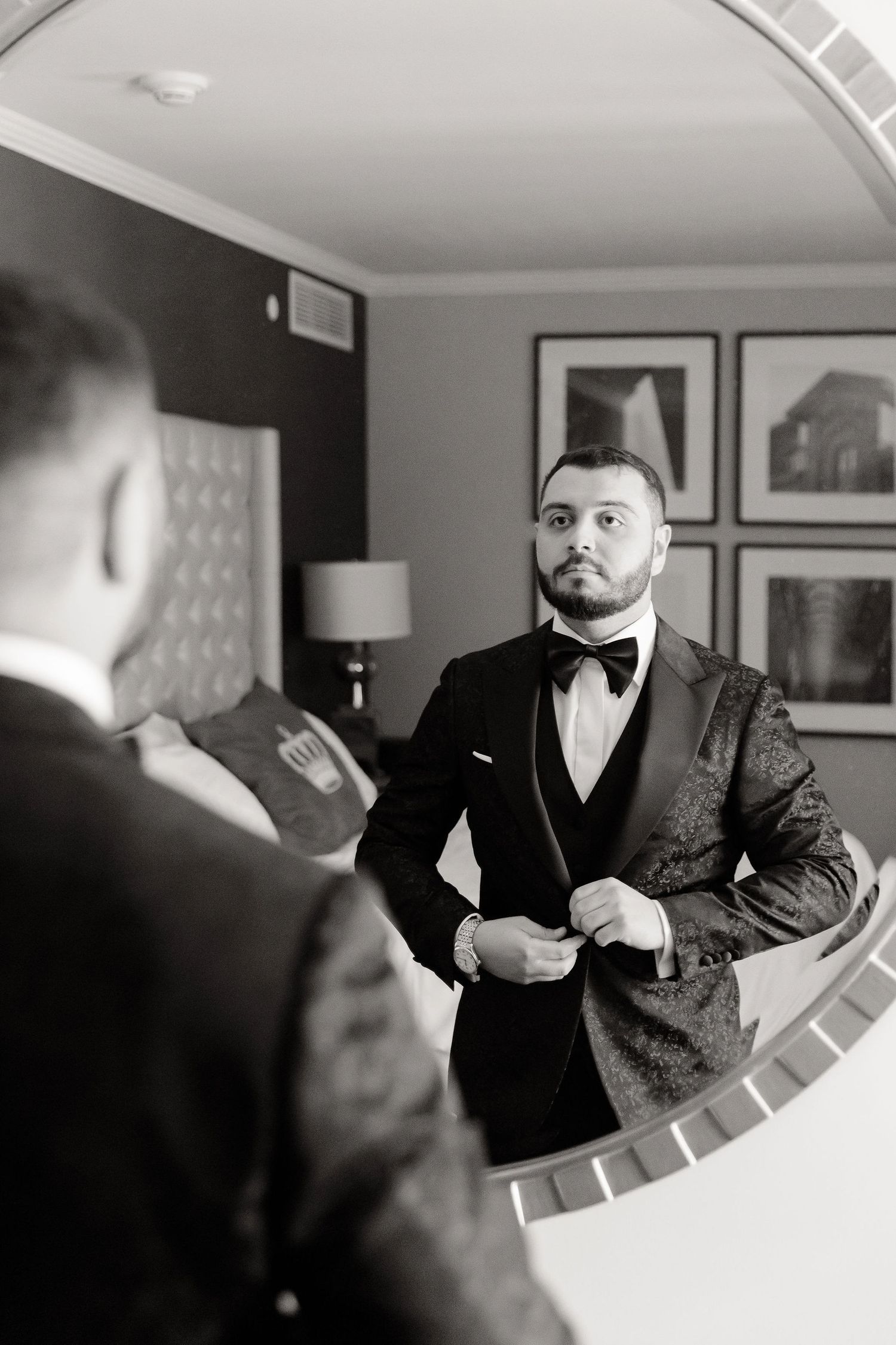 Black and white mirror reflection showing formal wear preparations in an interior setting.