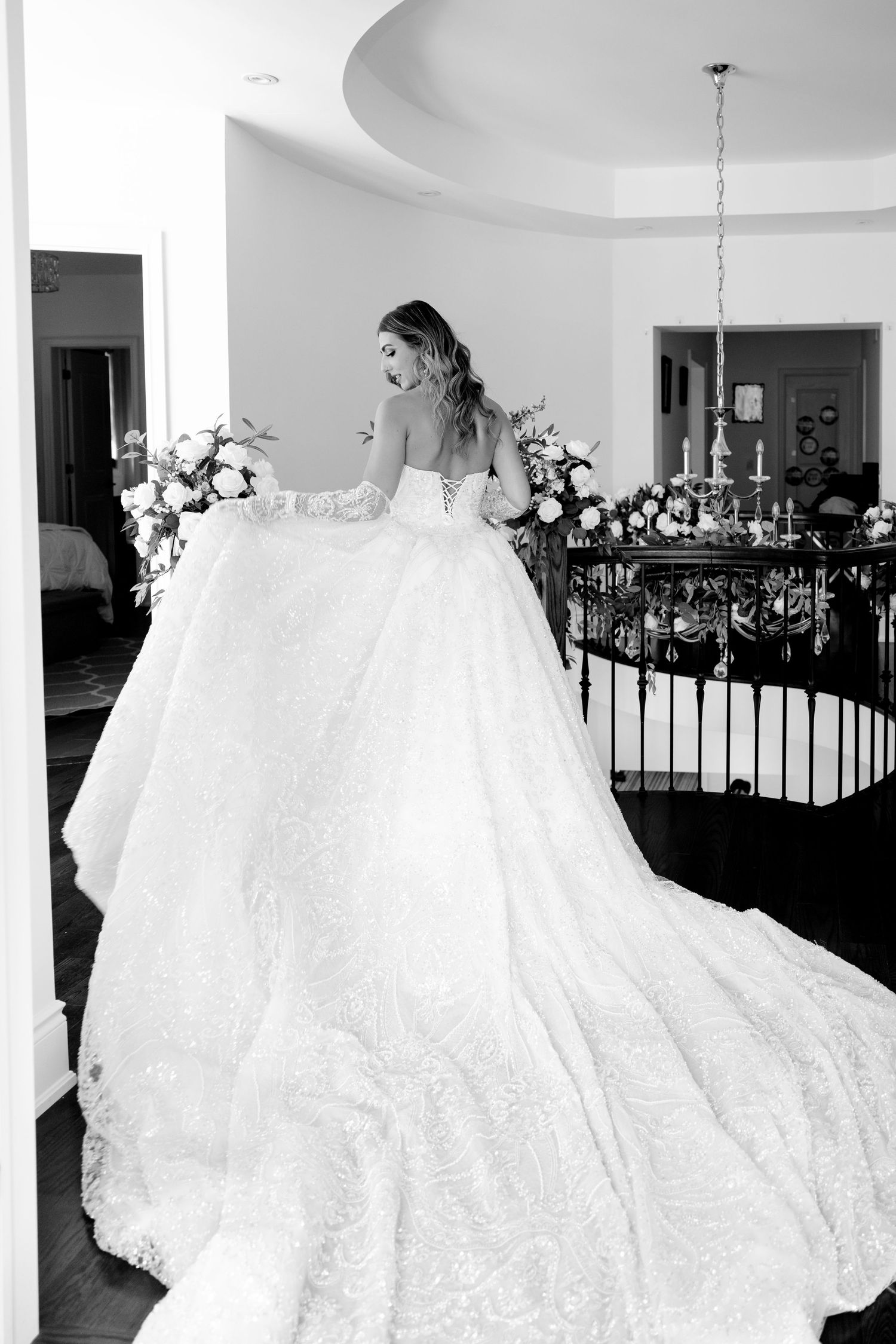 Dramatic black and white photo of a ballgown wedding dress with cathedral train in an elegant venue.
