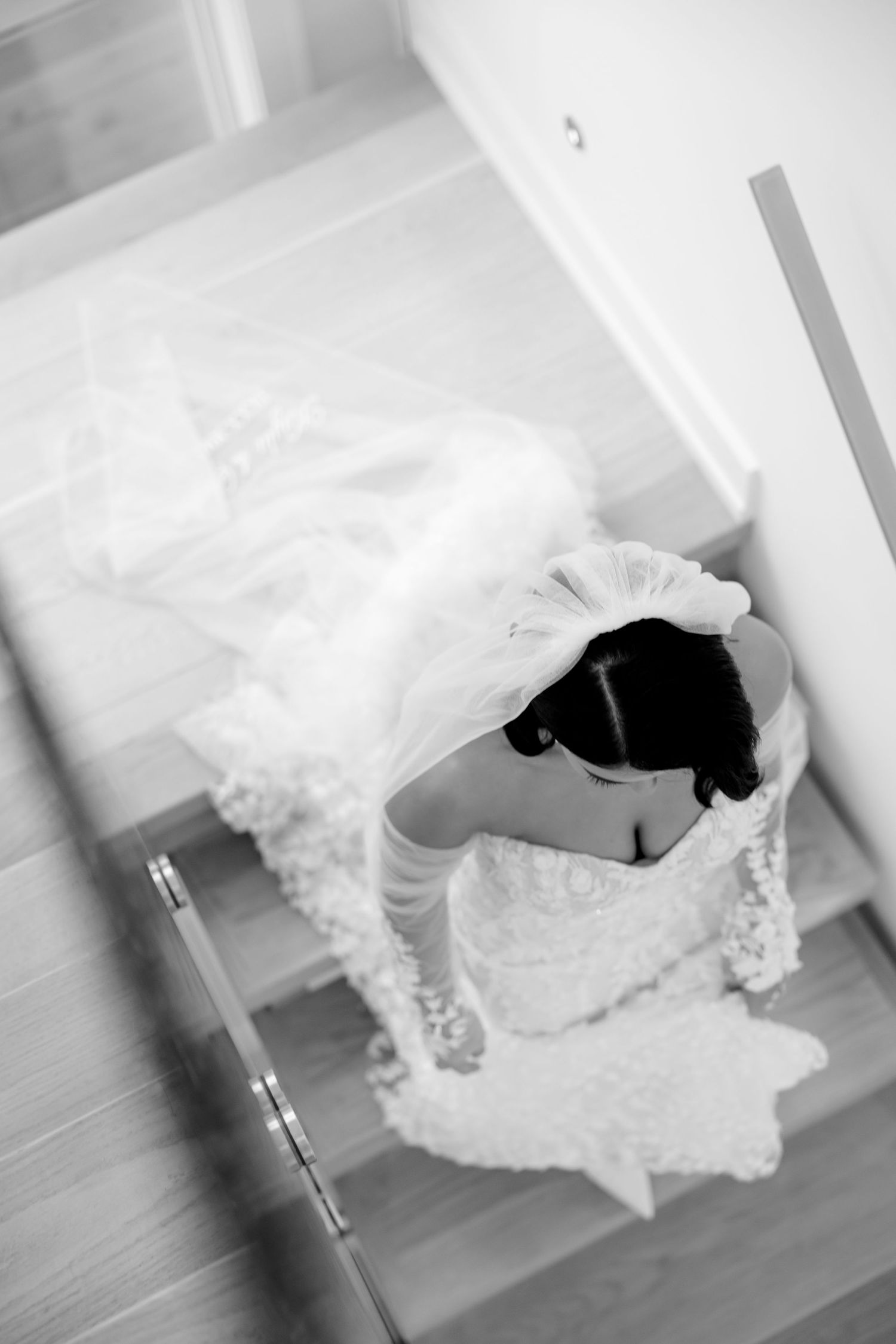 Overhead view of a bride's dress and veil flowing down wooden stairs.