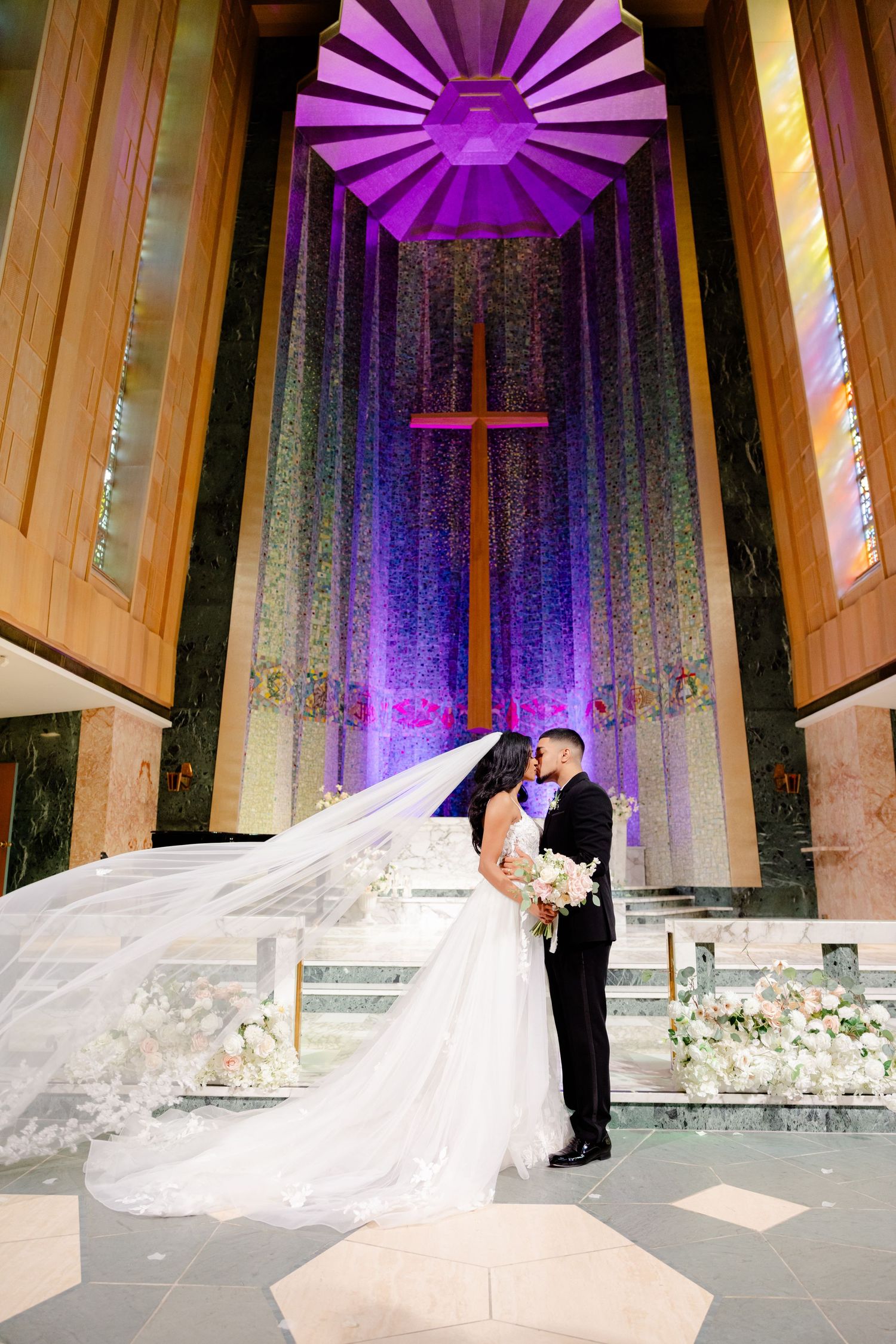 Cathedral wedding ceremony with dramatic purple lighting and sunburst ceiling detail.