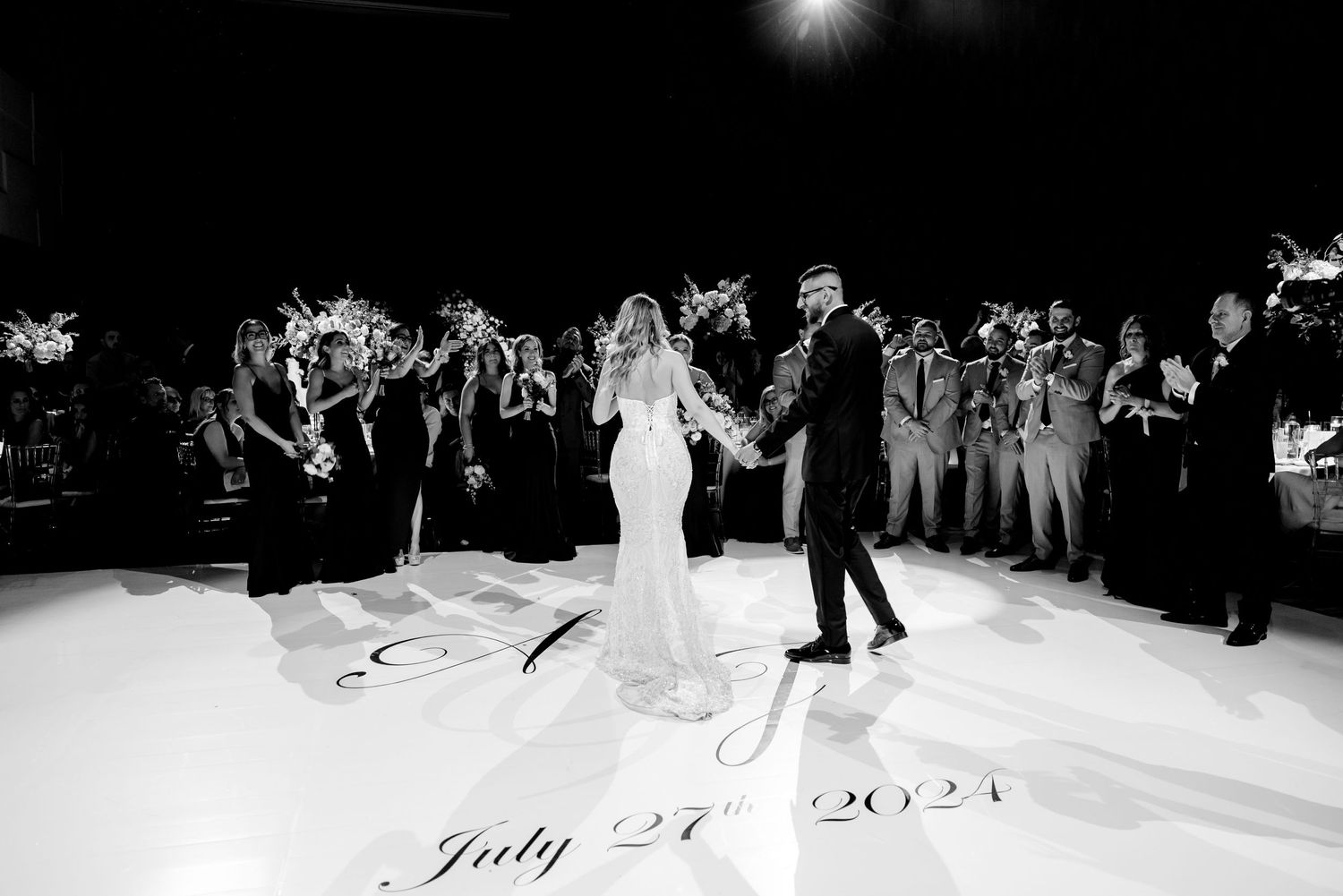 A black and white capture of newlyweds dancing on a floor with July 24 2021 inscription.