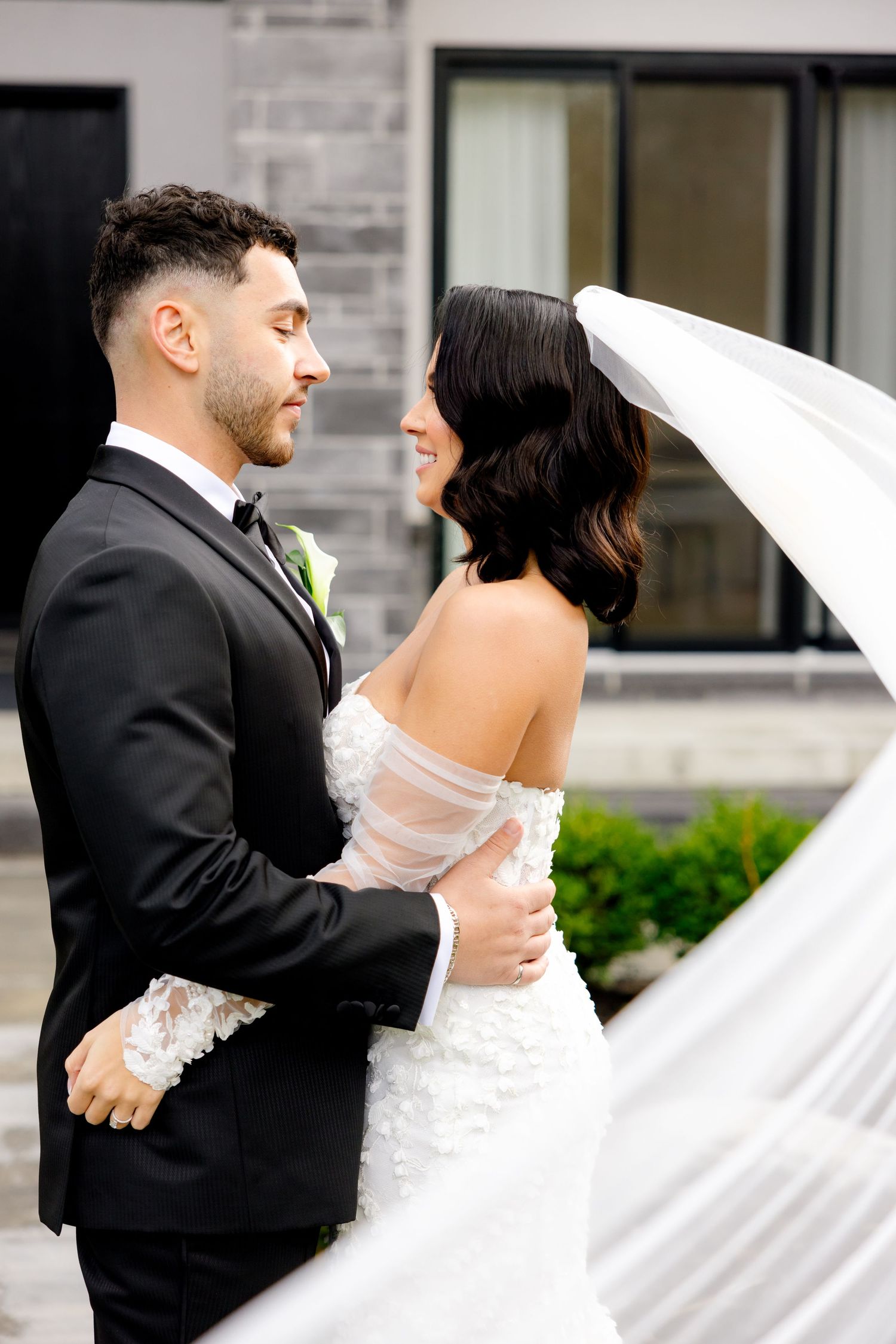 A candid wedding moment with the veil flowing dramatically in the breeze.