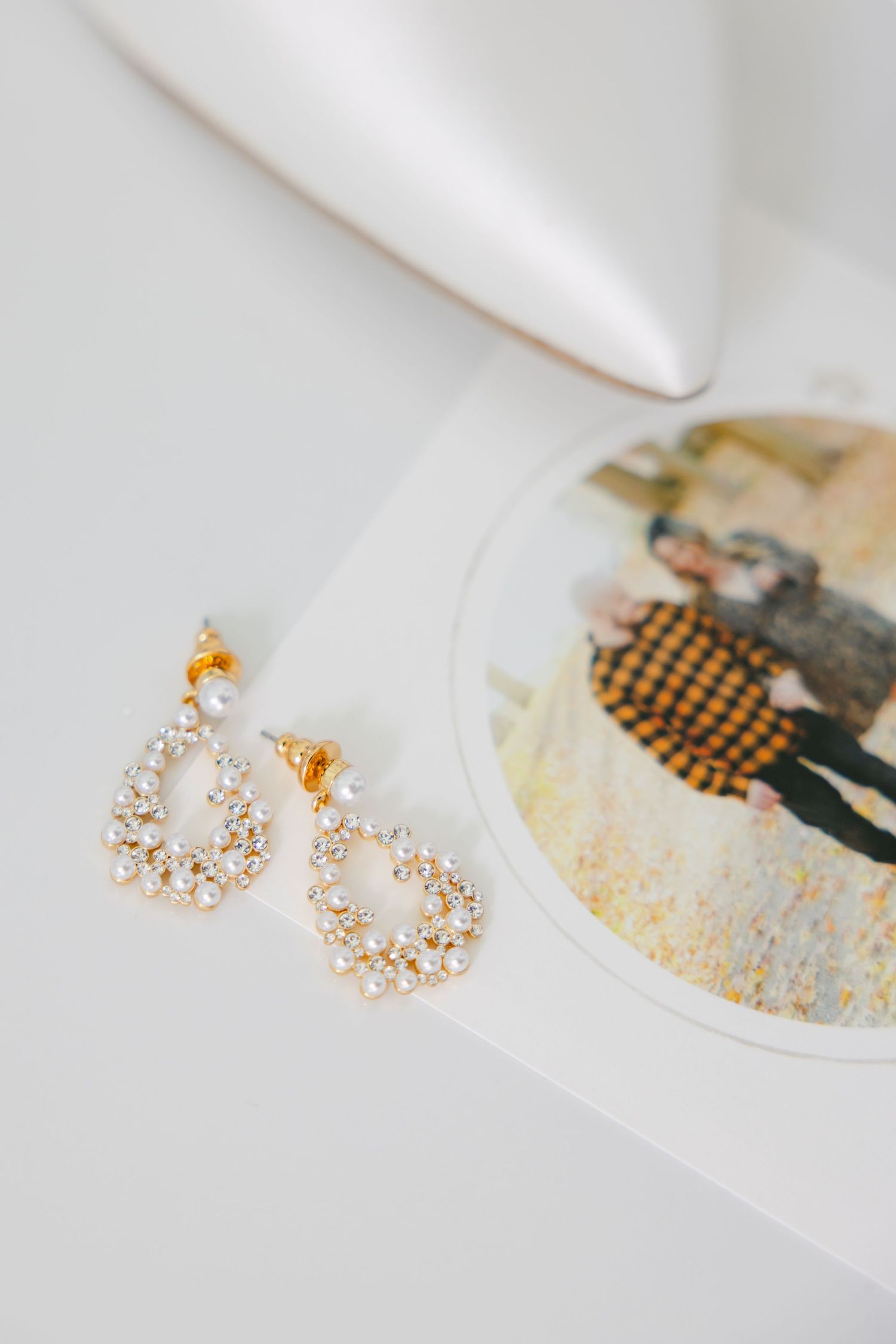 Crystal drop earrings and vintage-style illustration detail on white background.