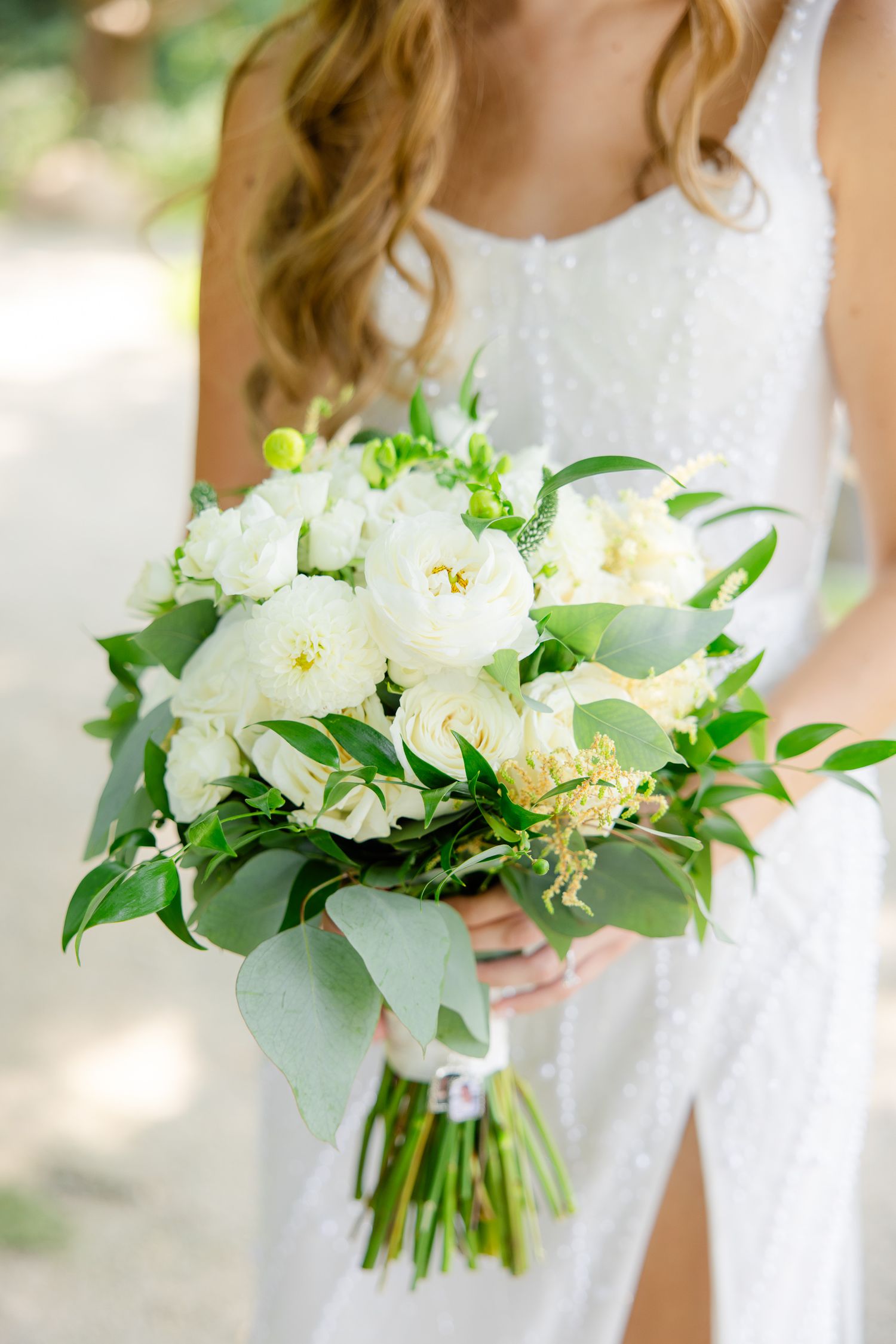 Close-up of an elegant white and green bridal bouquet with roses and eucalyptus.