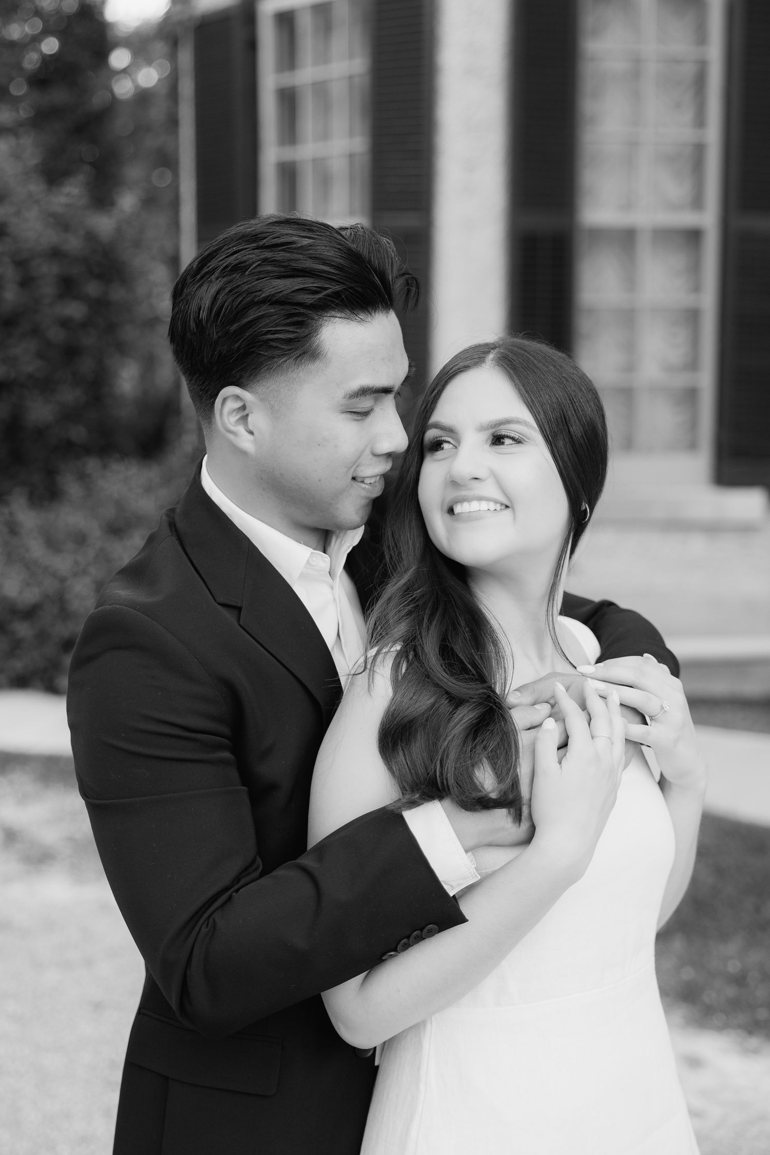 Black and white portrait of couple sharing tender moment in formal attire.