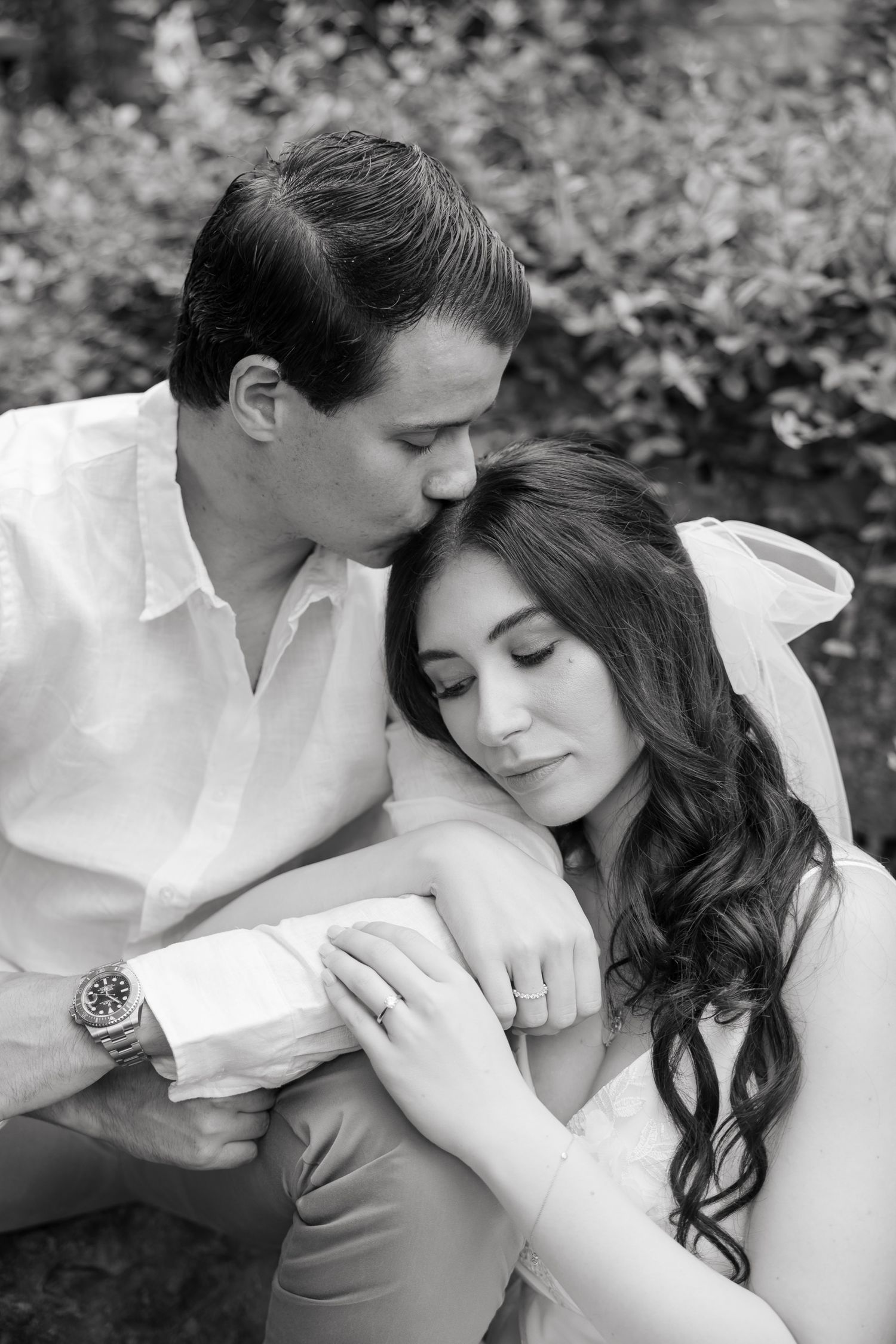 Black and white portrait of newlyweds sharing an intimate embrace outdoors.