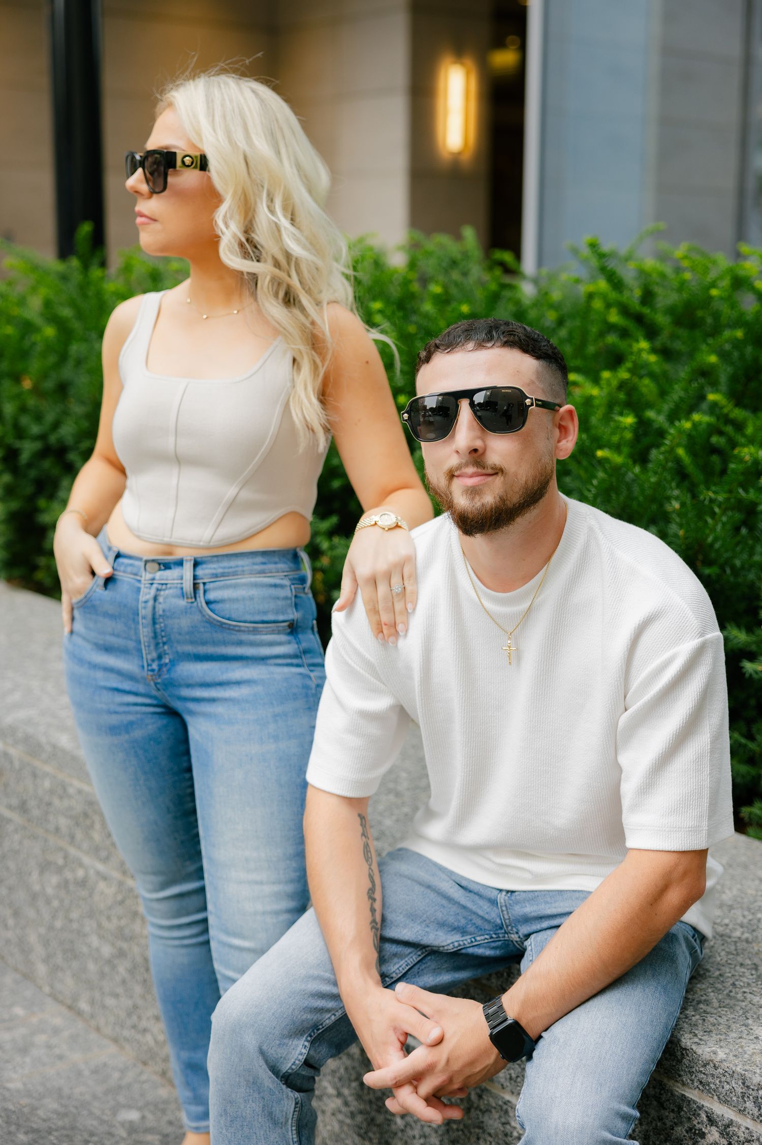 Modern couple in denim and white poses against contemporary urban setting.