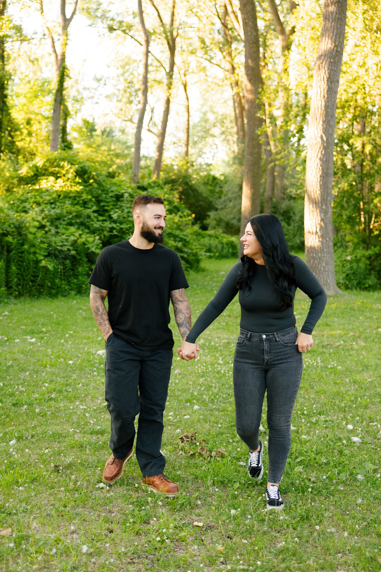 A couple holds hands while taking a stroll through a sunny wooded park.