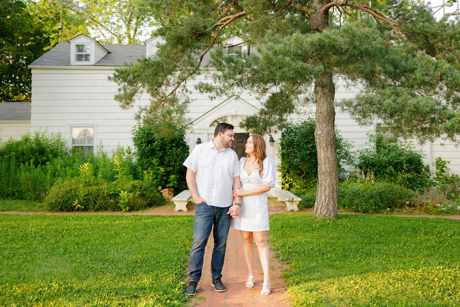 A couple shares a sweet moment while walking along a brick path in a garden setting.