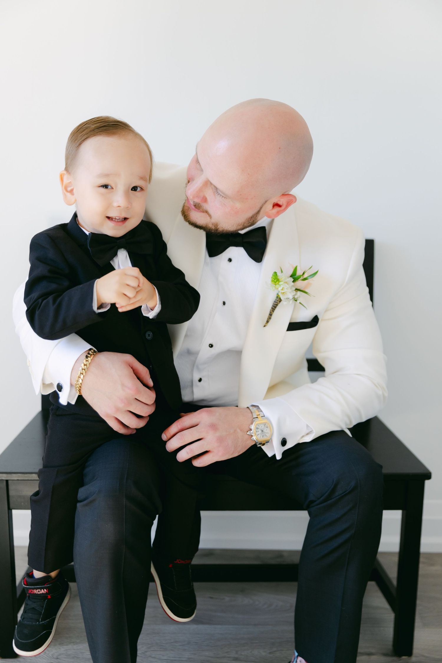 A candid moment showing two people in formal attire sharing smiles on a black bench.