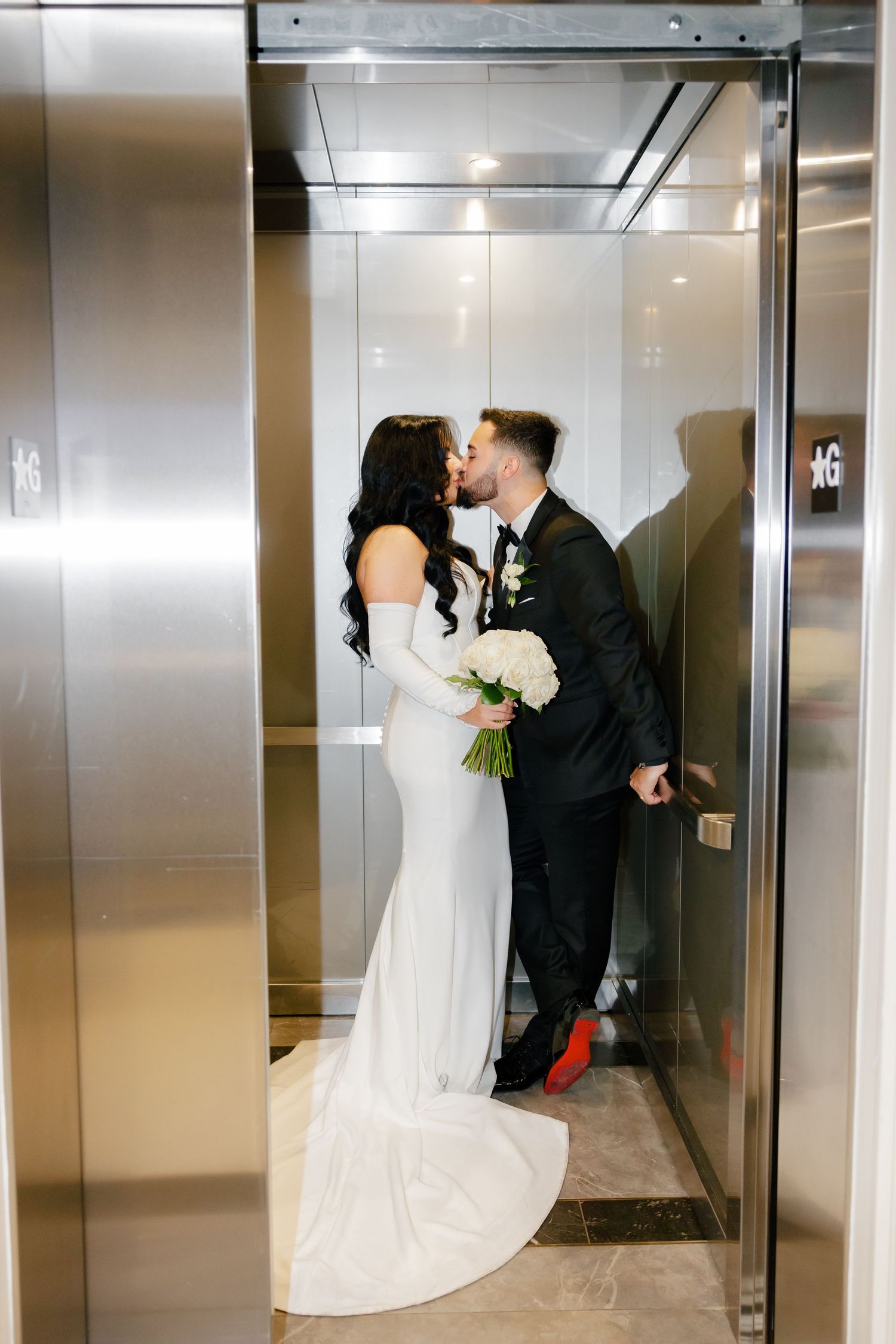 Romantic elevator wedding portrait with bride's flowing dress train and groom in classic tuxedo.