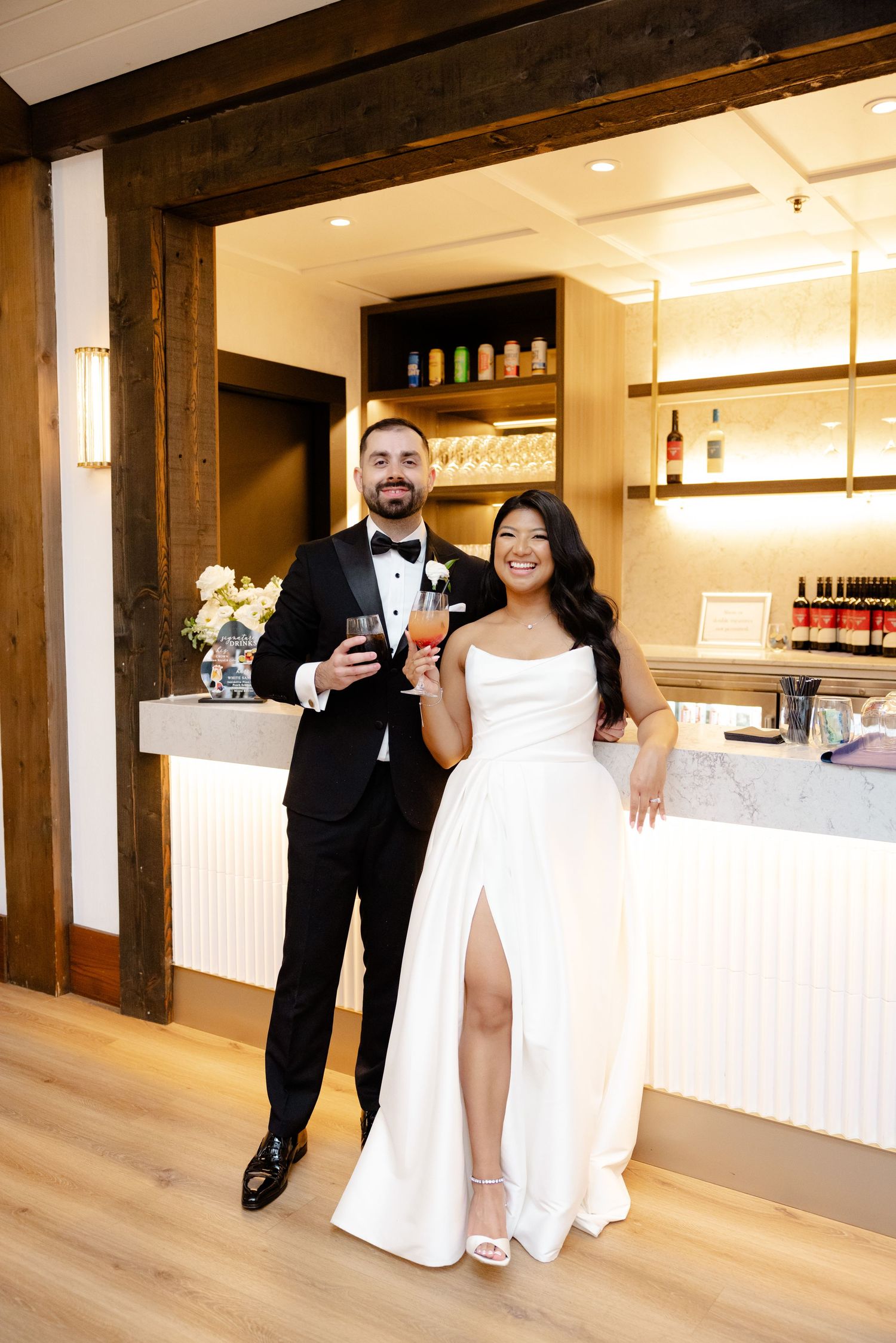 A celebratory moment at a wedding bar area with rustic wooden beam details.