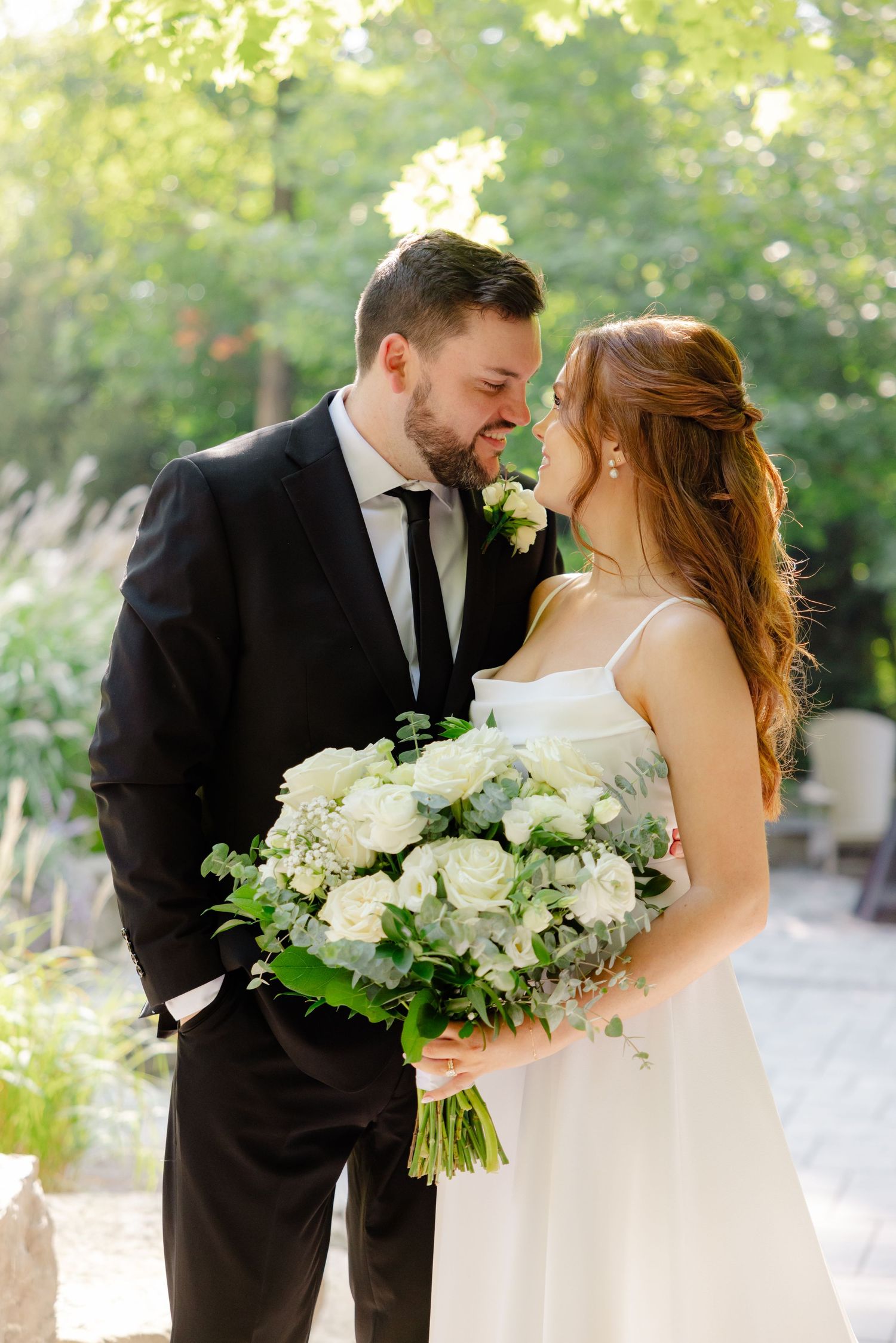 A candid wedding photo showing a couple sharing a loving moment with a lush white bouquet.