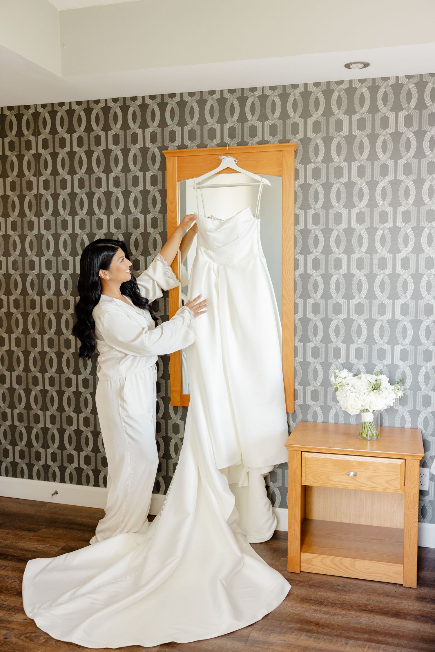 Elegant bridal preparation scene with white wedding gown and patterned wallpaper.