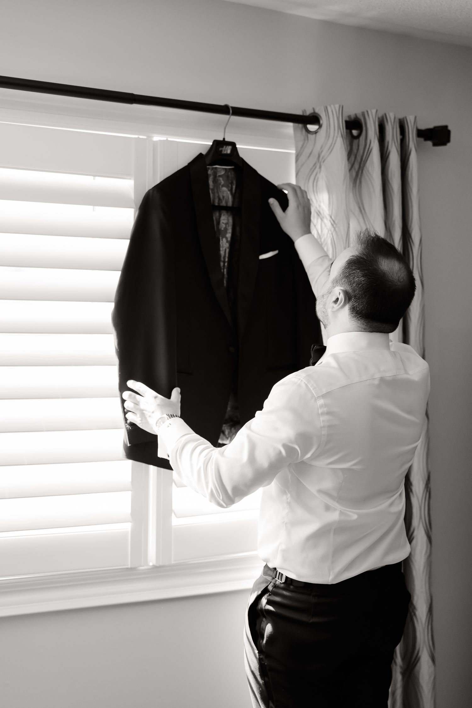 A sequence of black and white photos showing someone adjusting a suit jacket from different angles.