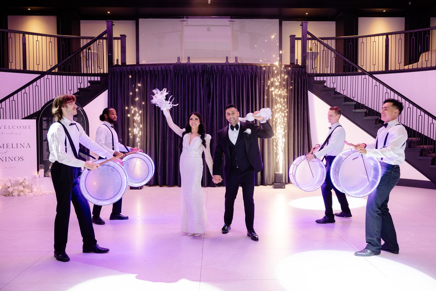Wedding celebration with drummers performing around newlyweds in a beautifully lit venue space.