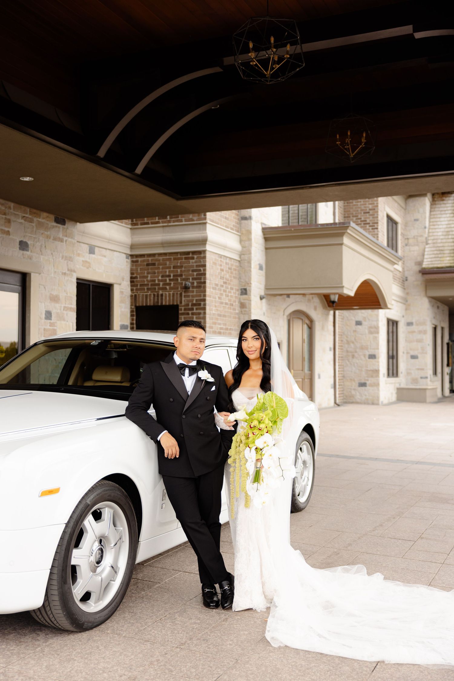Romantic wedding photoshoot featuring formal attire and luxury white car at upscale venue.
