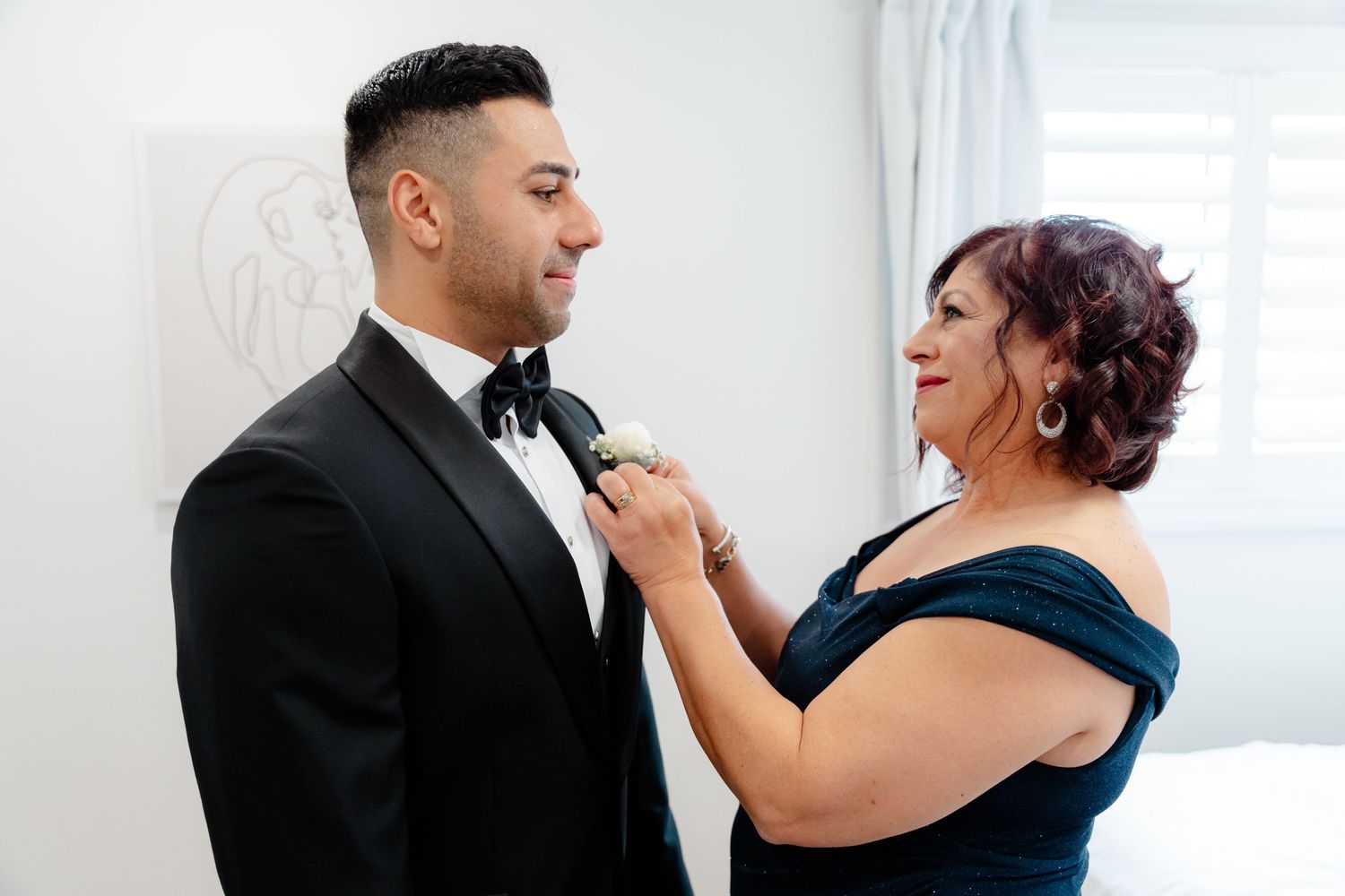 A joyful moment shared between two people while adjusting formal attire.