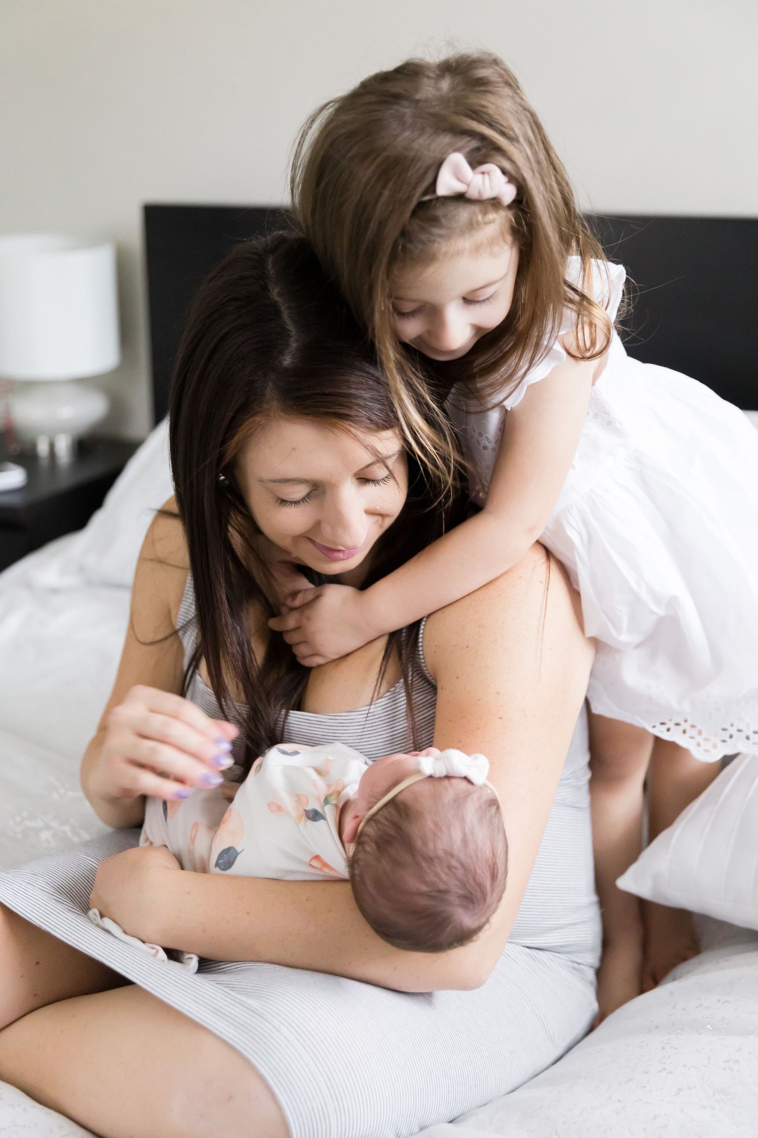 Sweet family moment captured on white bed with newborn.