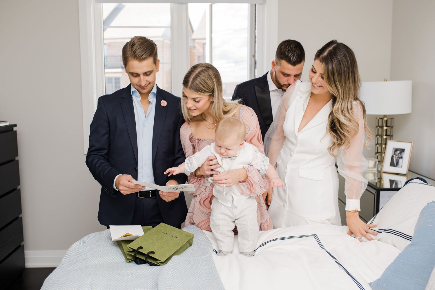Family gathering around baby while looking at documents in bright indoor setting.