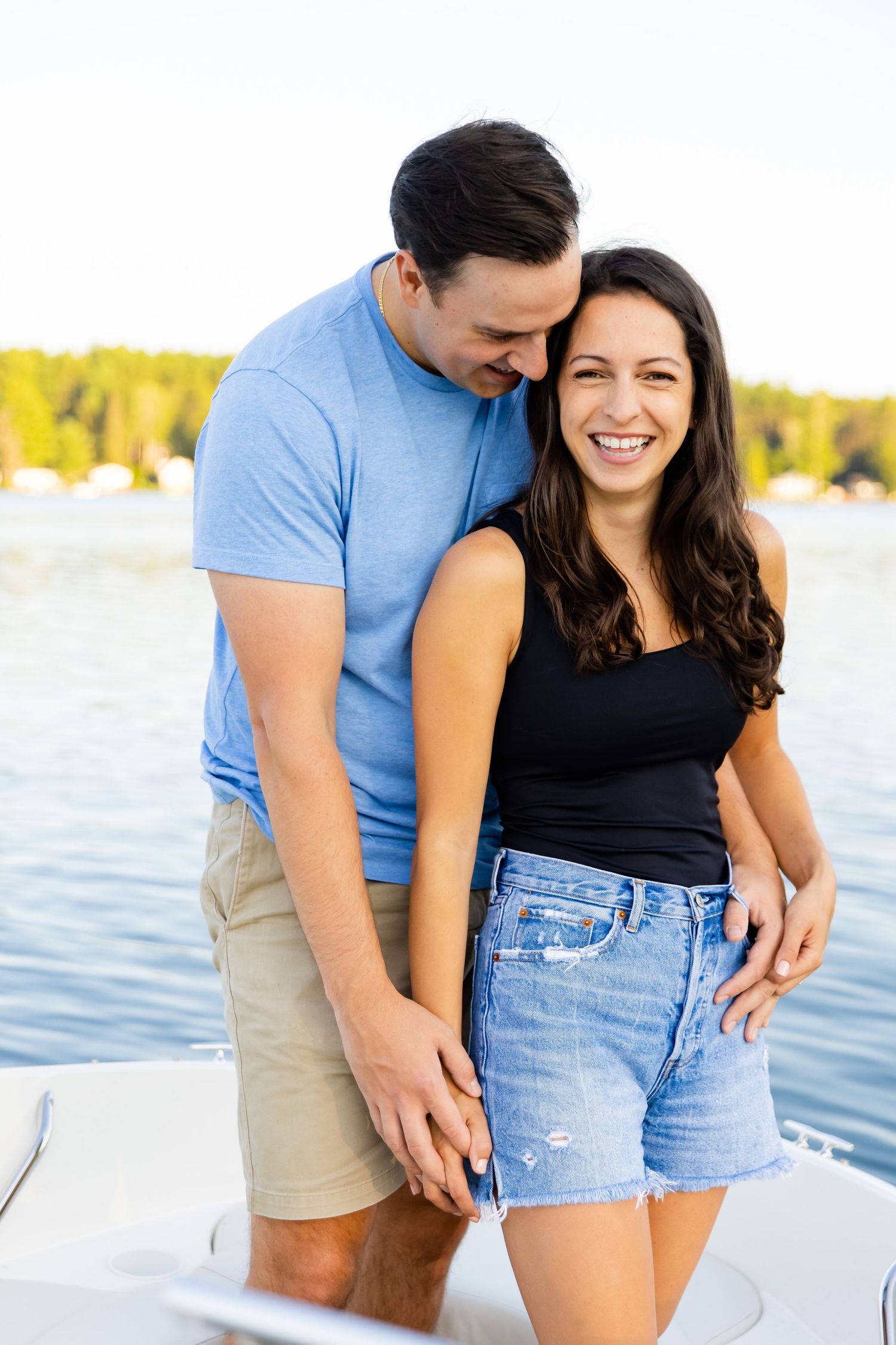 A romantic couple share an intimate moment together while standing on a boat deck near the water.