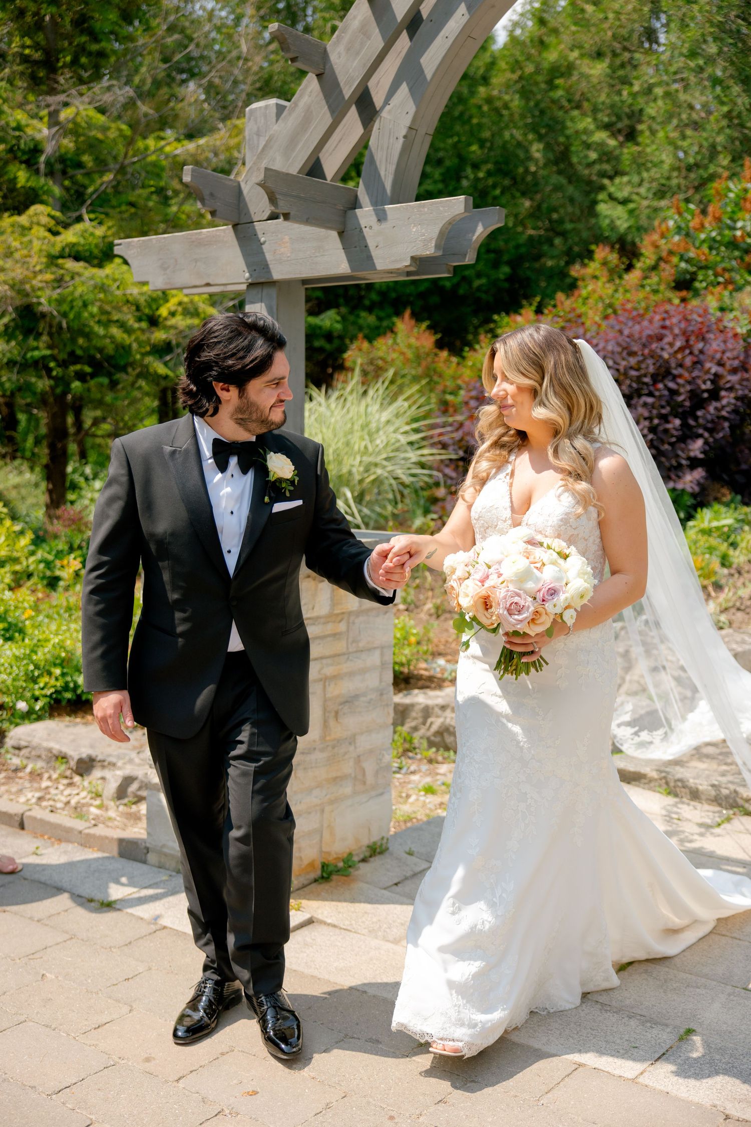 A couple shares a joyful moment under a garden arbor surrounded by summer blooms.