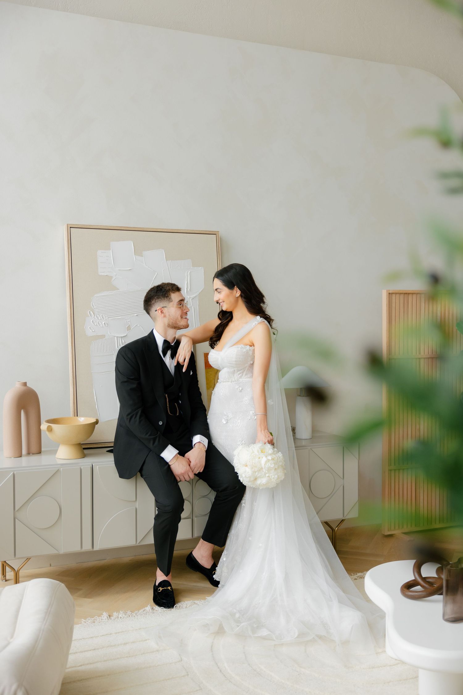 Romantic wedding portrait in minimalist setting with modern furniture and natural light.