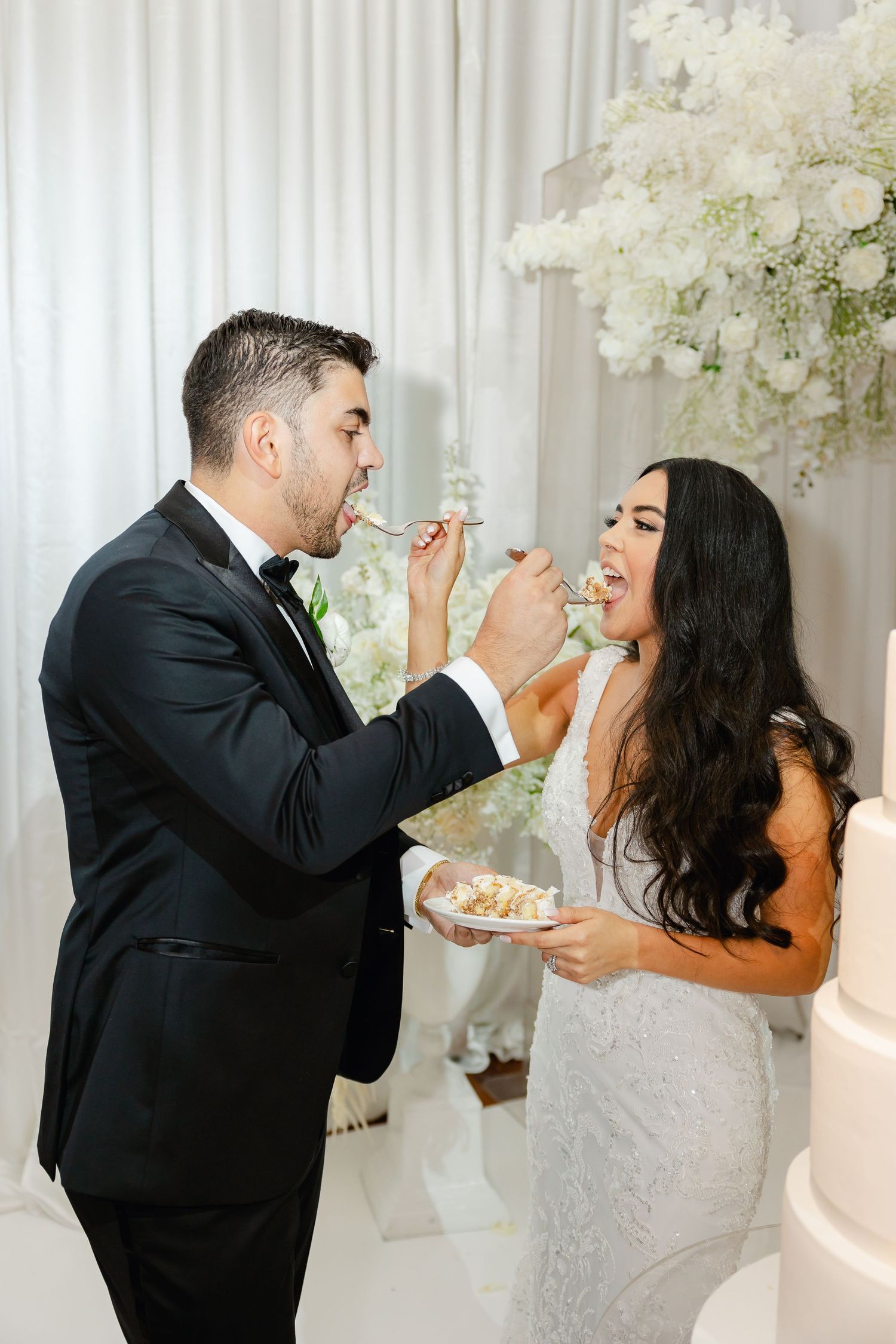 Playful moment of newlyweds feeding each other wedding cake at their reception.