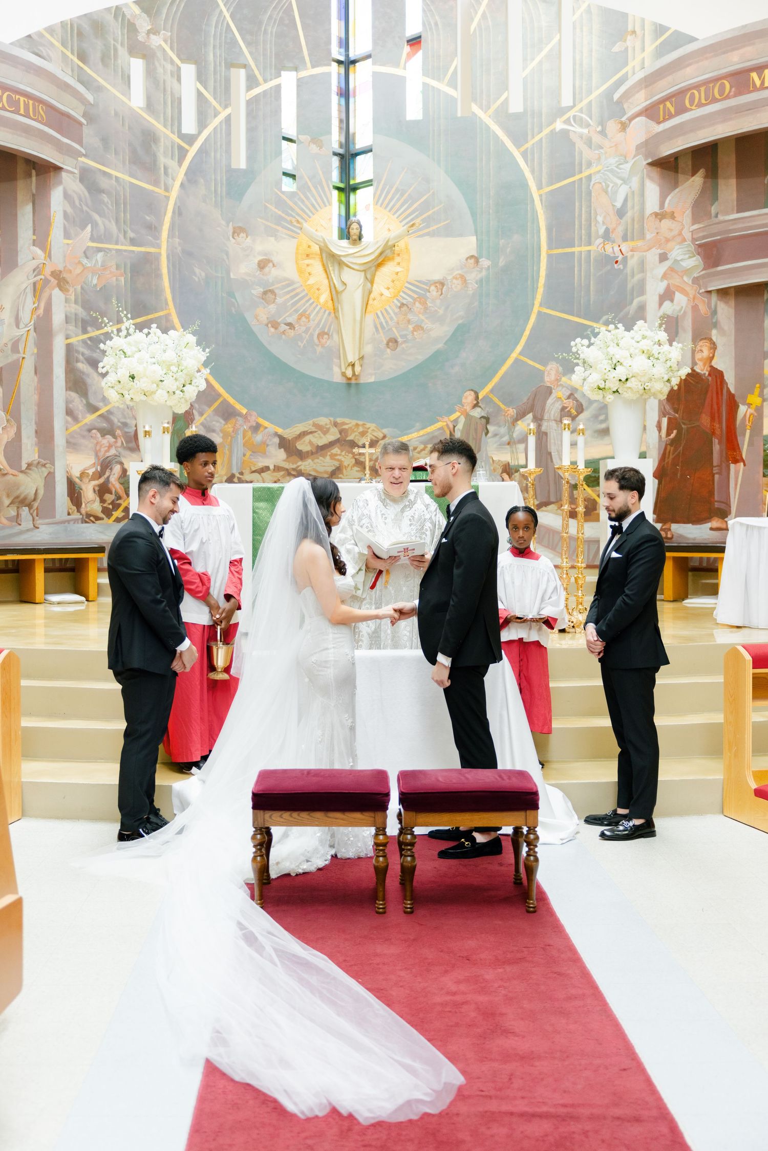 A beautiful church wedding ceremony with ornate religious artwork and white floral decorations.