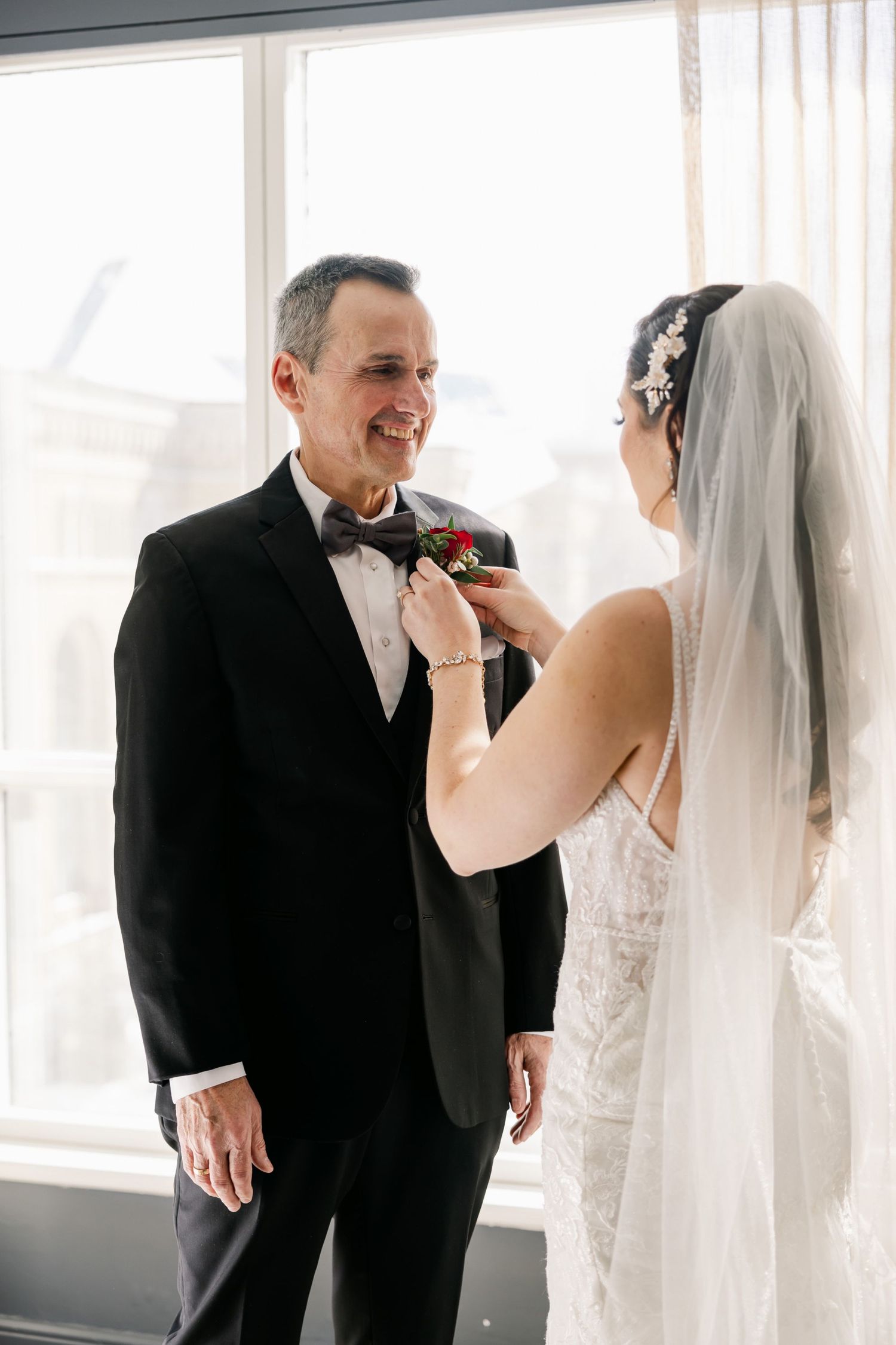 Candid moment of wedding preparation as boutonniere is pinned on formal attire.