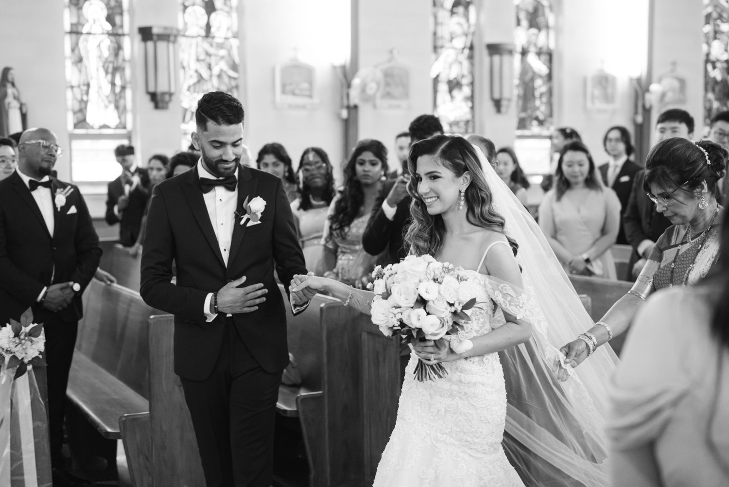 A black and white photograph of a wedding ceremony in progress inside a traditional church.