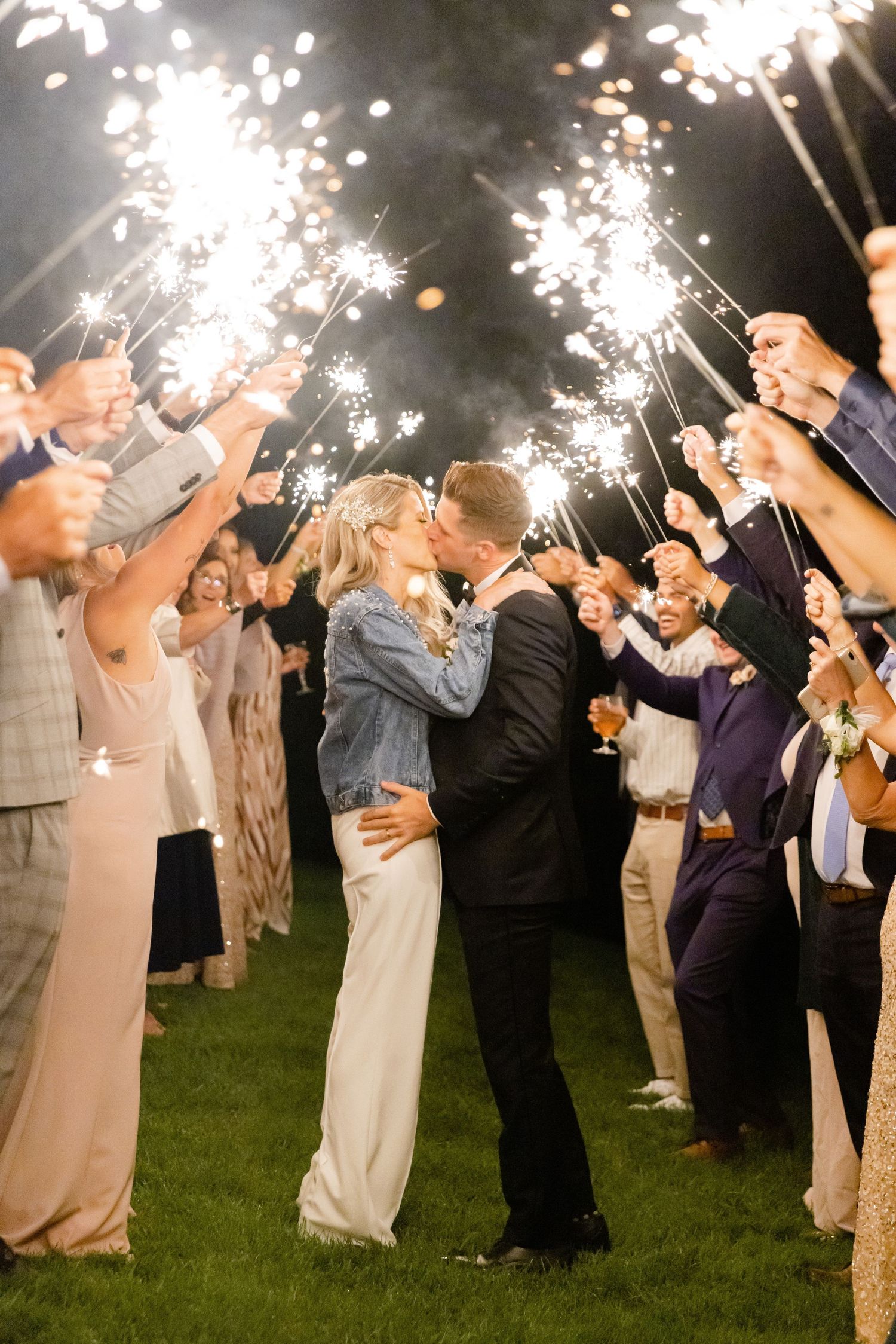 Couple shares romantic moment under sparkler arch during wedding reception sendoff.